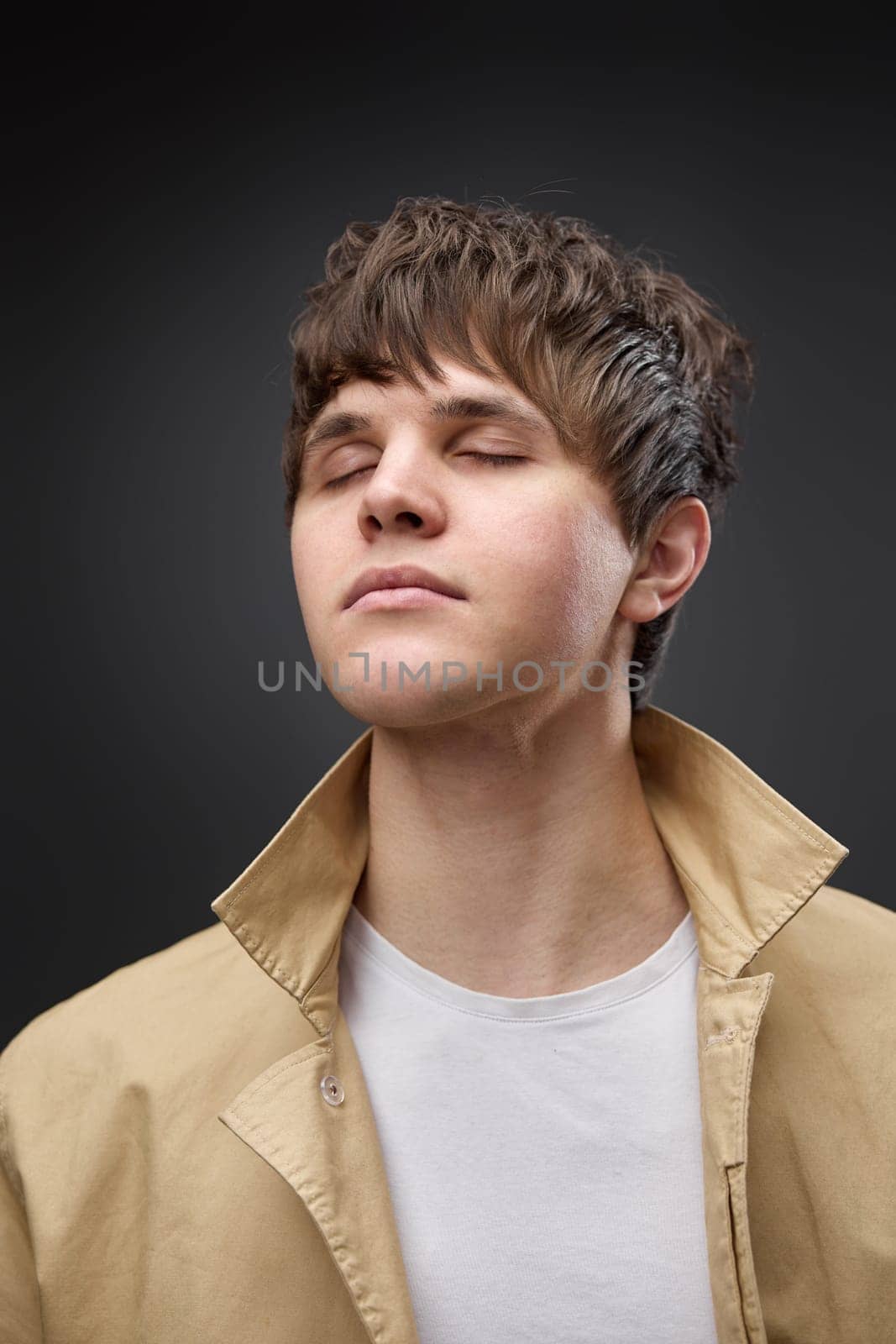 calm caucasian man with hairstyle in coat on black background. fashion modern style look