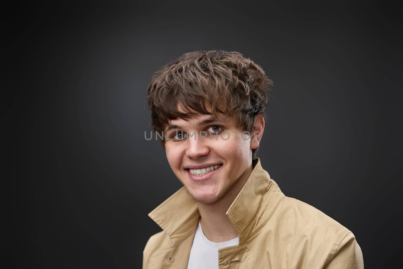 smiling caucasian man with hairstyle in coat on black background. fashion modern style look