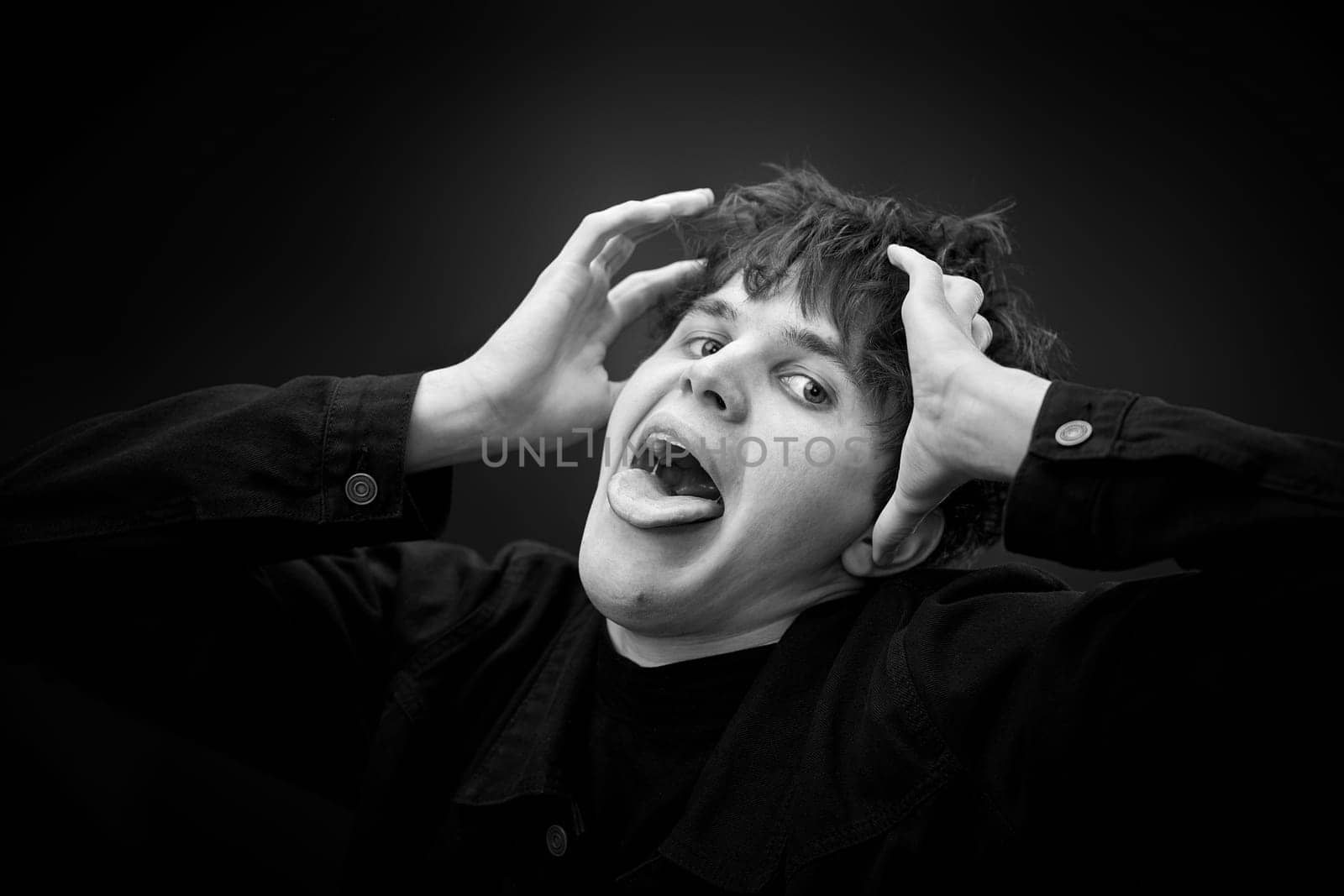 portrait of crazy young man showing the tongue and grimacing . black and white