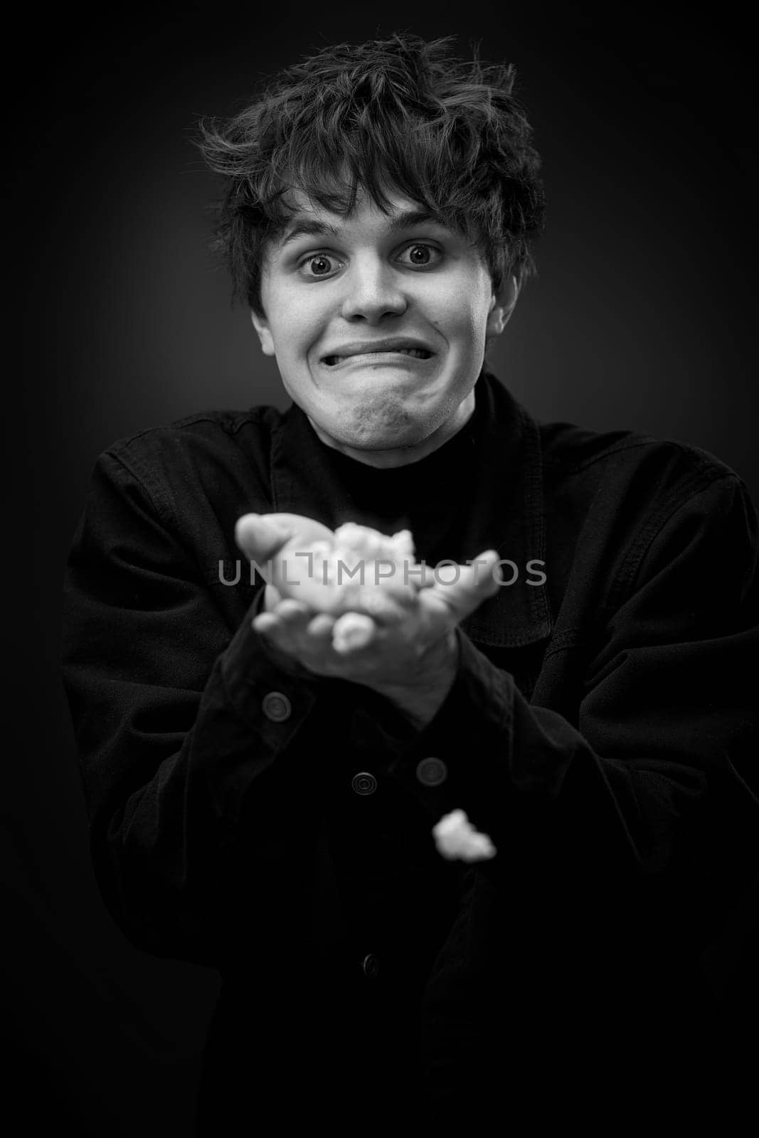 portrait of crazy young man throwing up popcorn and grimacing . black and white