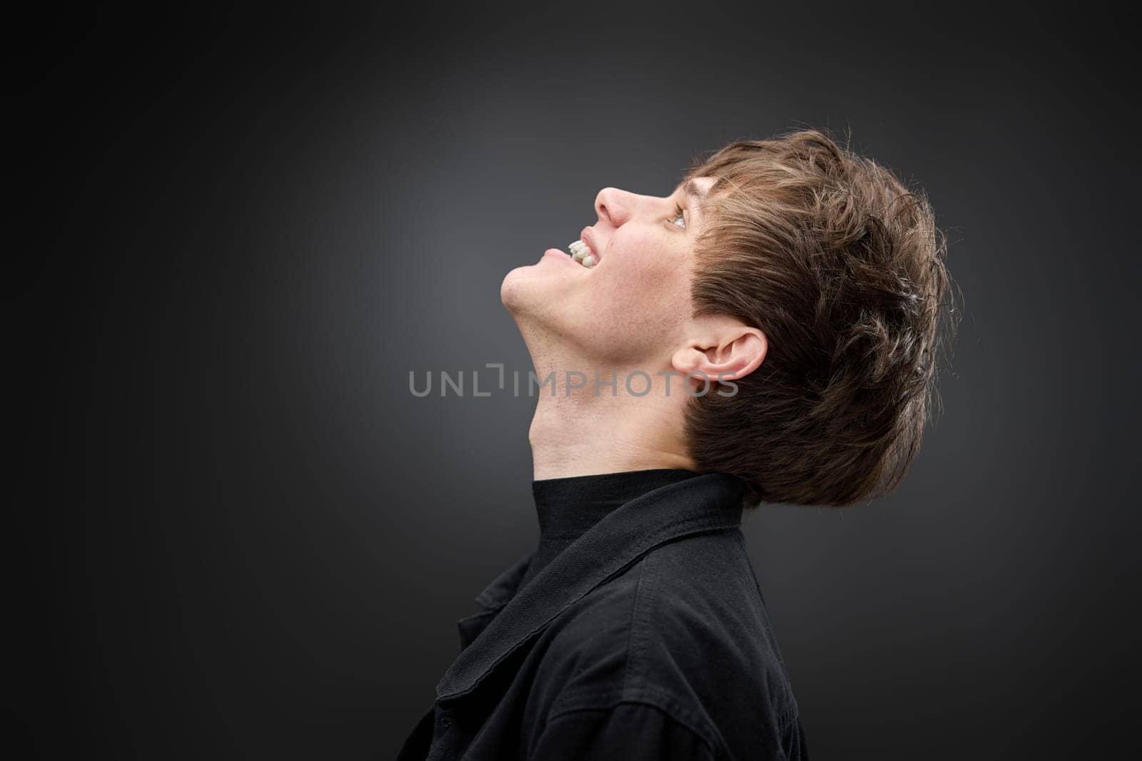 side view of positive handsome man with hairdo on black background. copy space