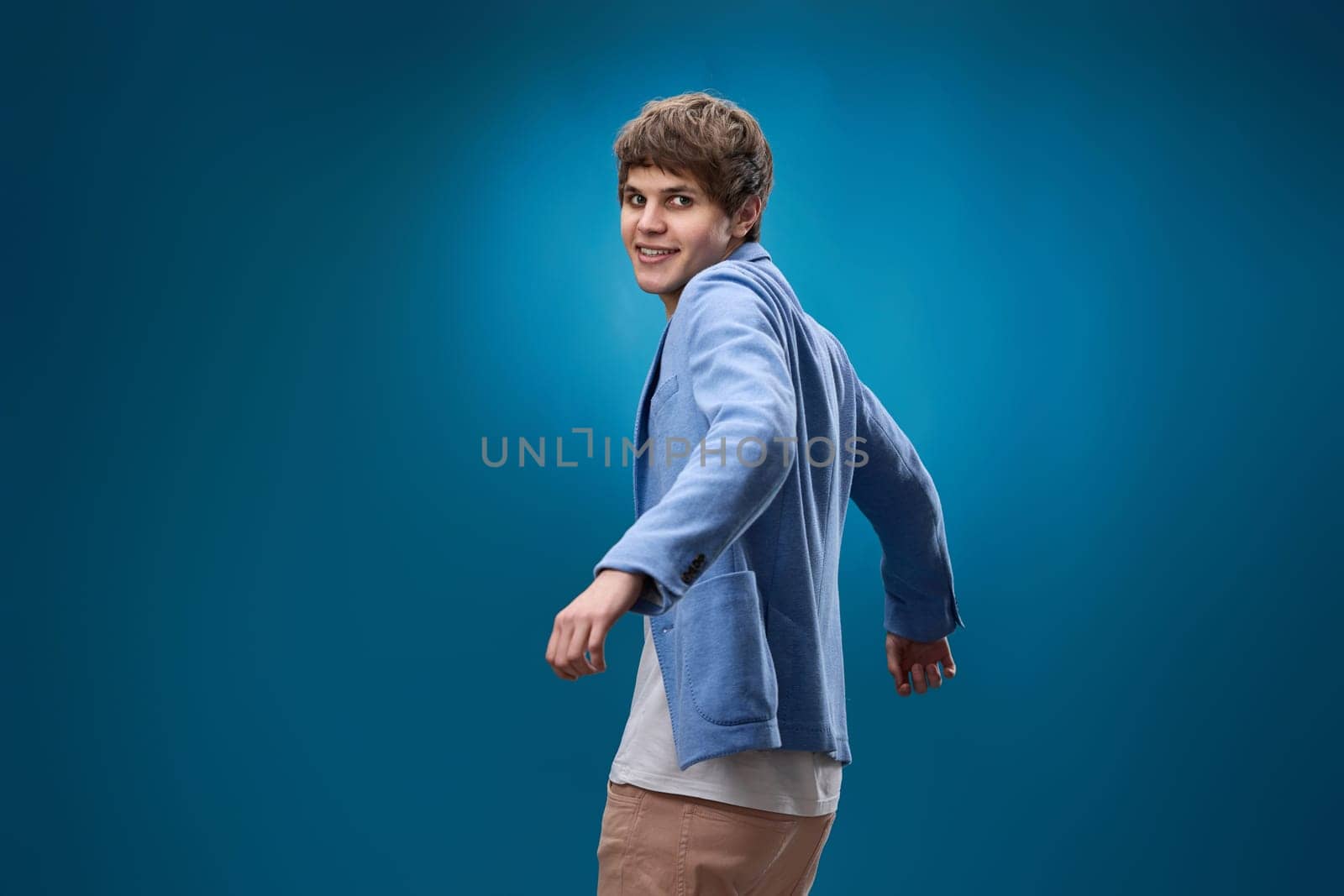 positive happy caucasian man in yellow sweatshirt dancing on blue background