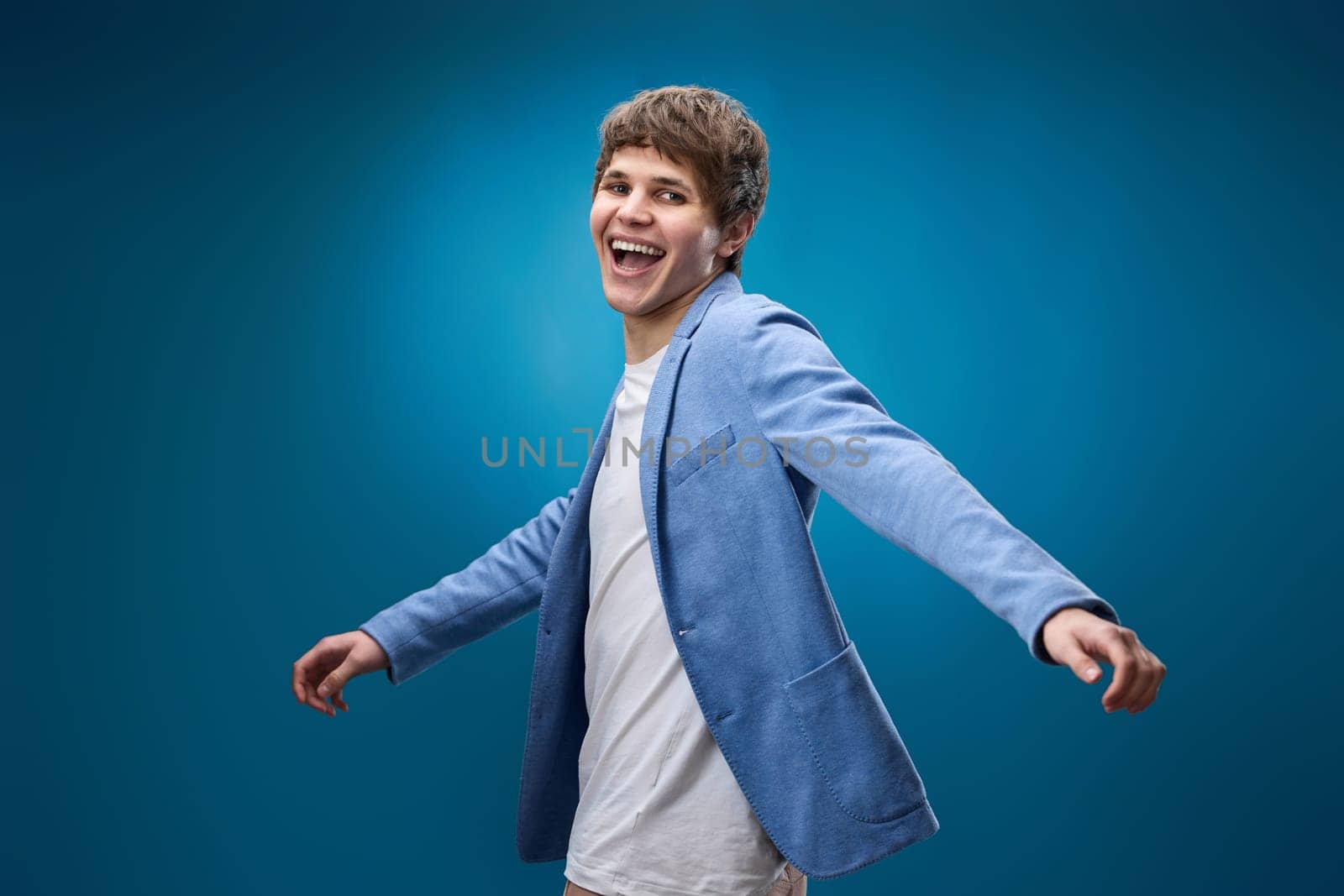 positive happy caucasian man in yellow sweatshirt dancing on blue background