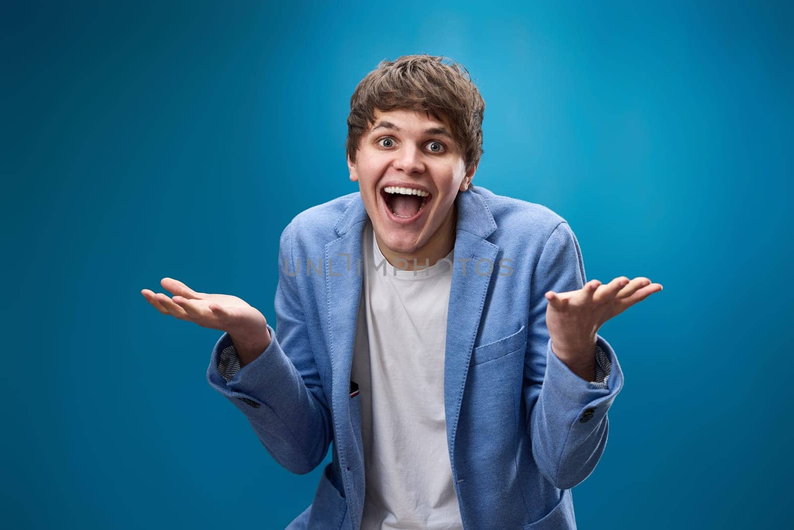 happy shocked man with surprise expression and excited face on blue studio background