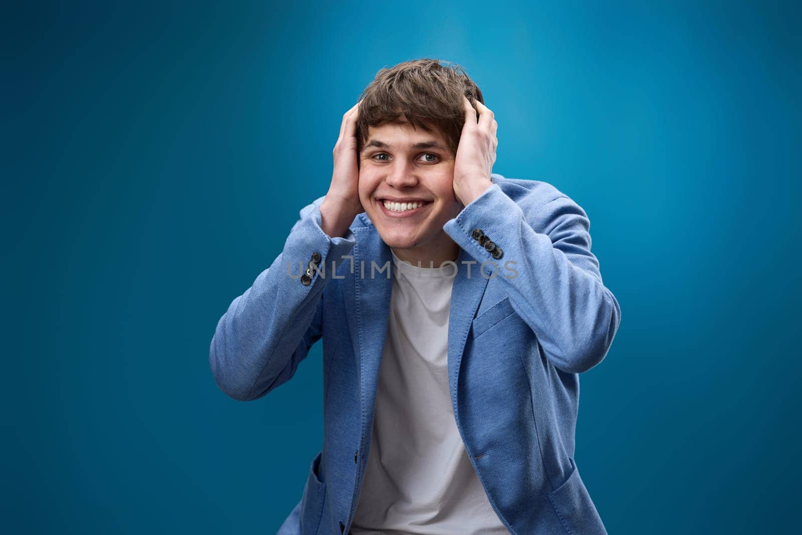smiling shocked man with surprise expression and excited face on blue studio background