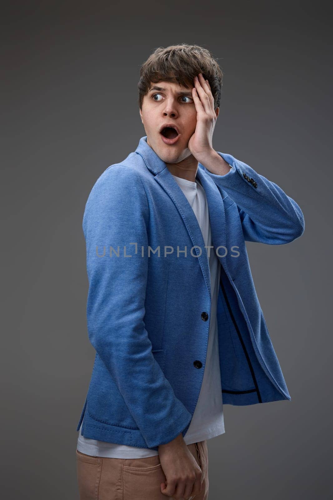 shocked man with surprise expression, fear and excited face on gray studio background