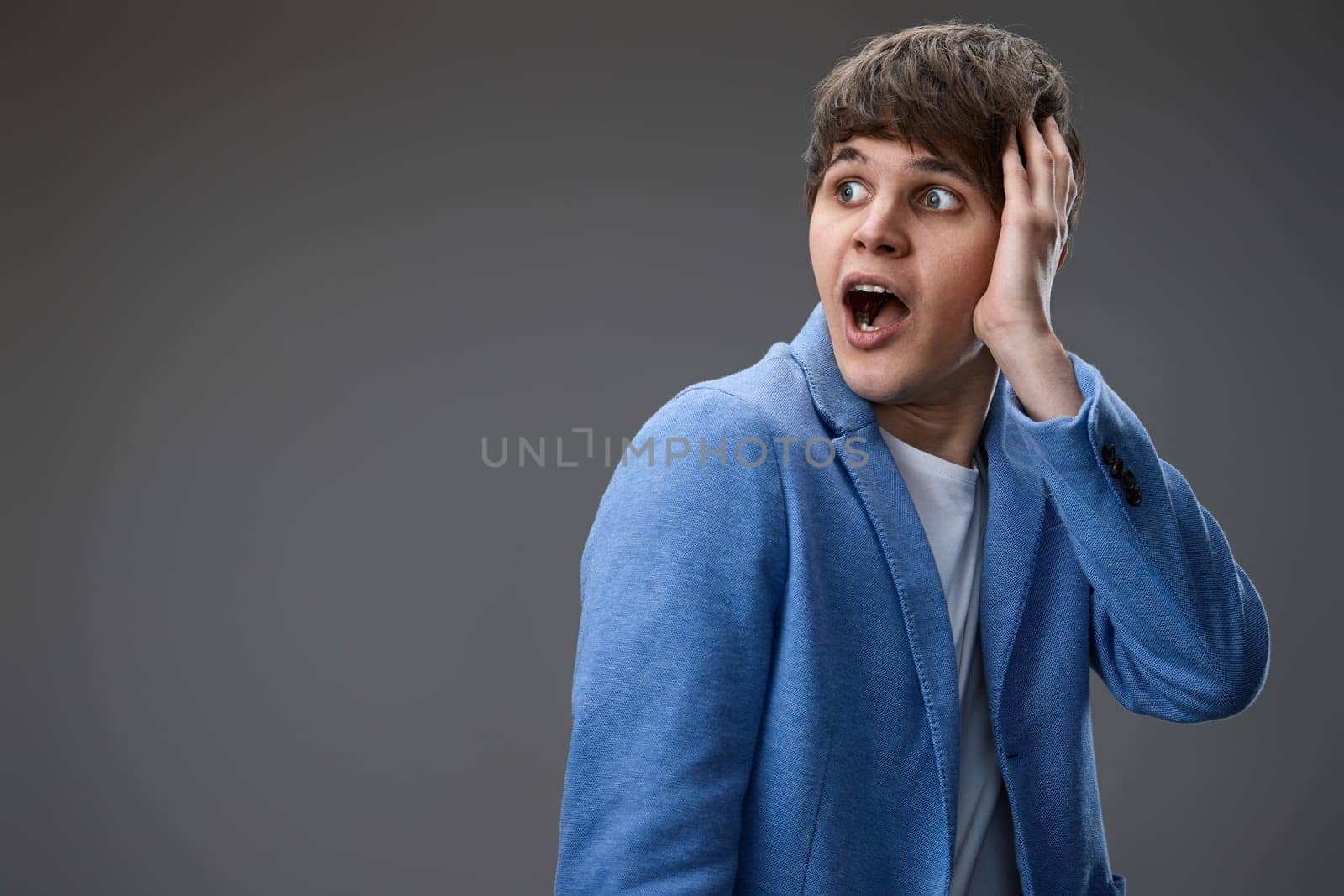 shocked man with surprise expression, fear and excited face on gray studio background. copy space