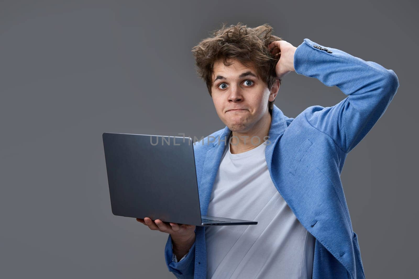 Funny and crazy caucasian nerd man with laptop on gray background