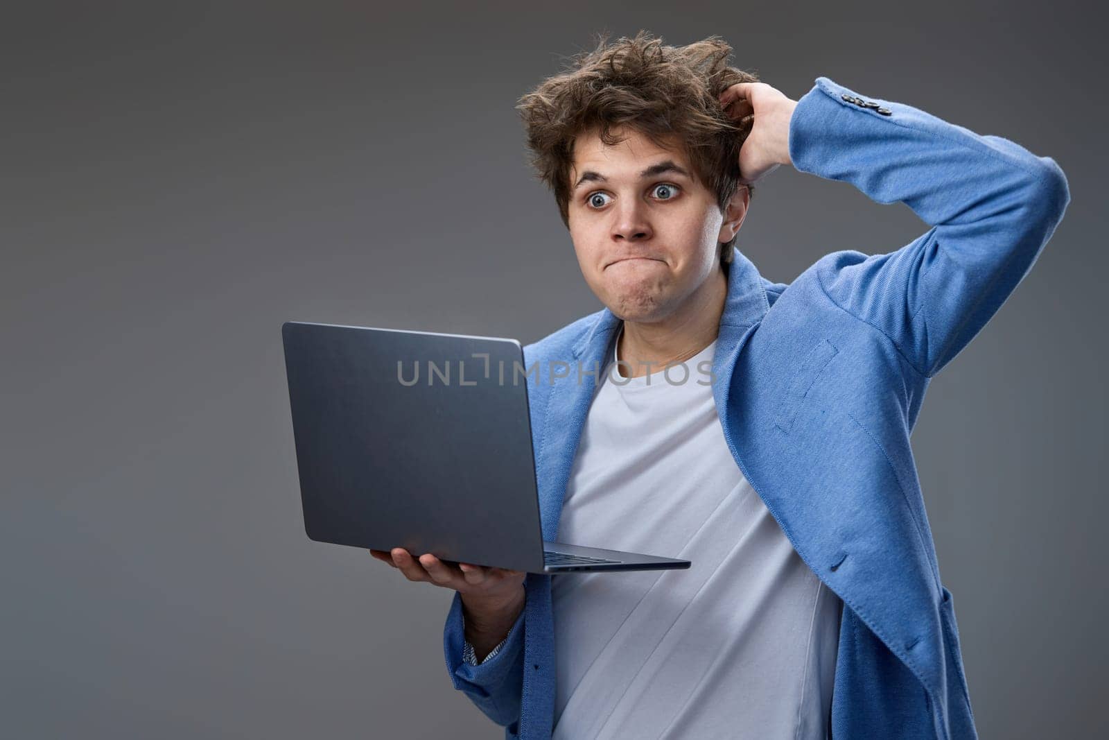 Funny and crazy caucasian geek man with laptop on gray background