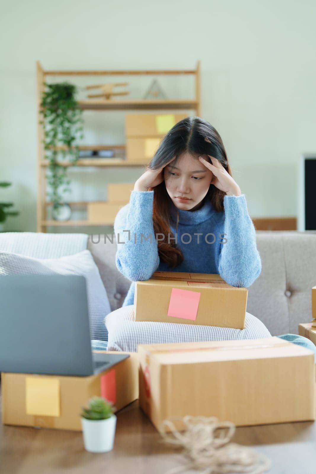 Starting small business entrepreneur of independent Asian woman showing her face worried about the sales of her business not reaching the target set. SME concepts.