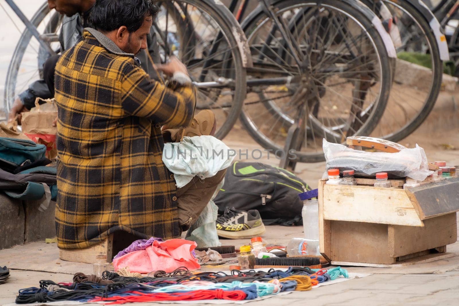 Chandigarh, India - circa 2023 : street side cobbler sitting on road and mending shoes in the winter months in sector 17 chandigarh during morning showing how the poor earn a living