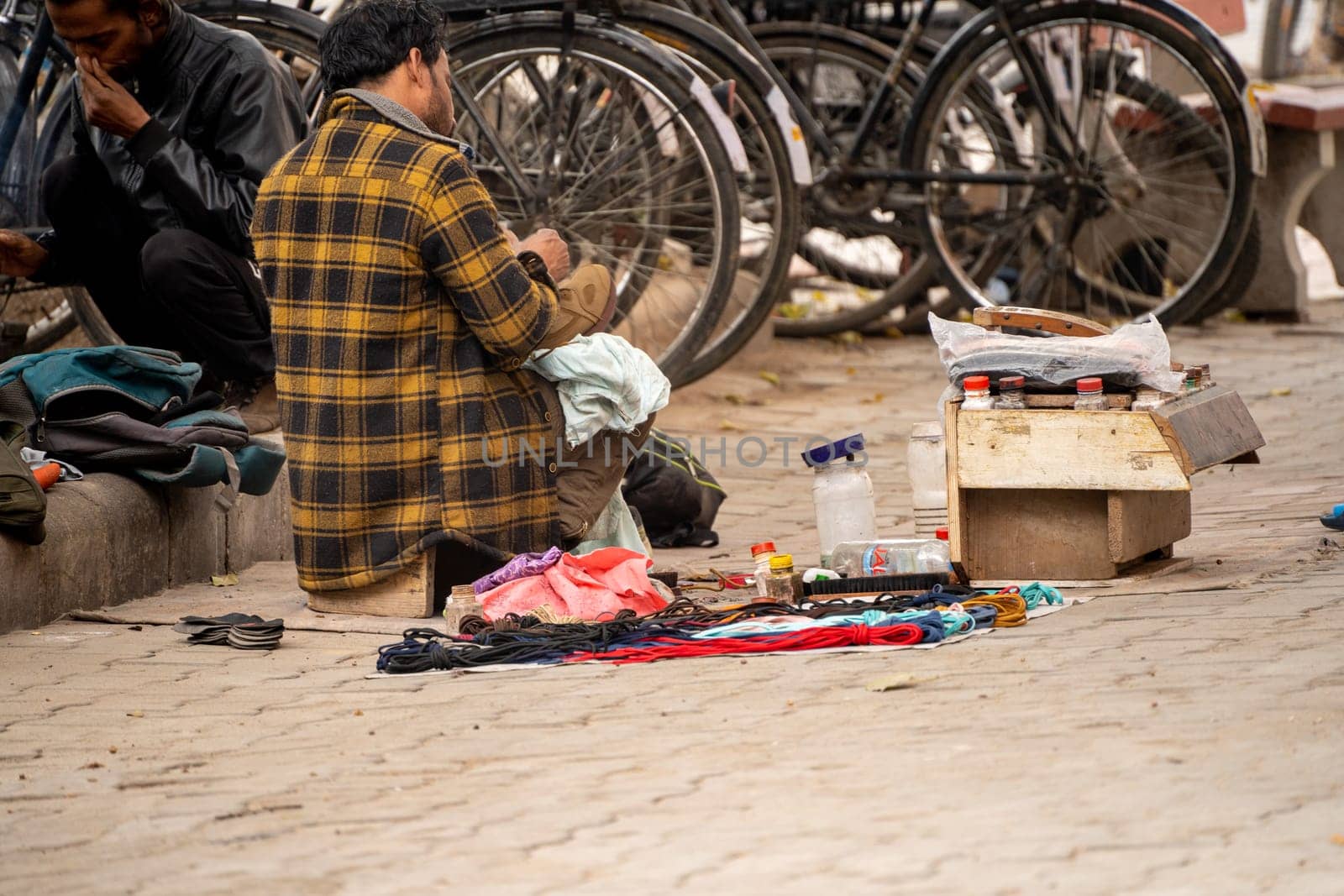 street side cobbler sitting on road and mending shoes in the winter months in sector 17 chandigarh during morning showing how the poor earn a living by Shalinimathur