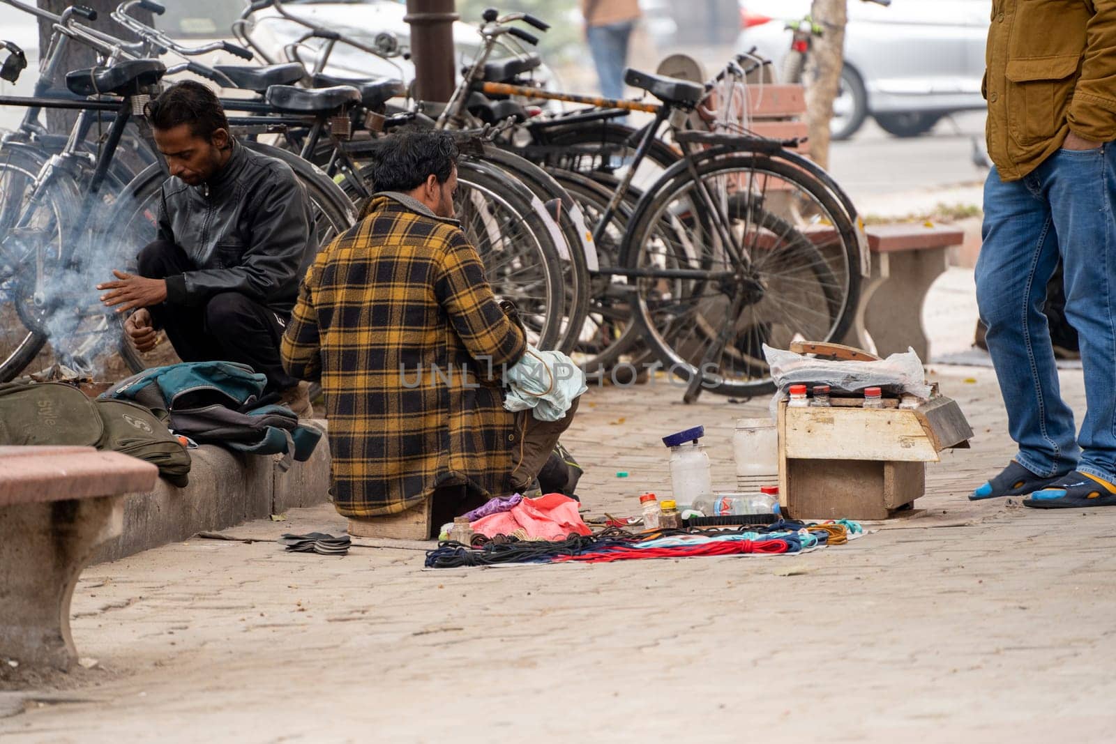 street side cobbler sitting on road and mending shoes in the winter months in sector 17 chandigarh during morning showing how the poor earn a living by Shalinimathur