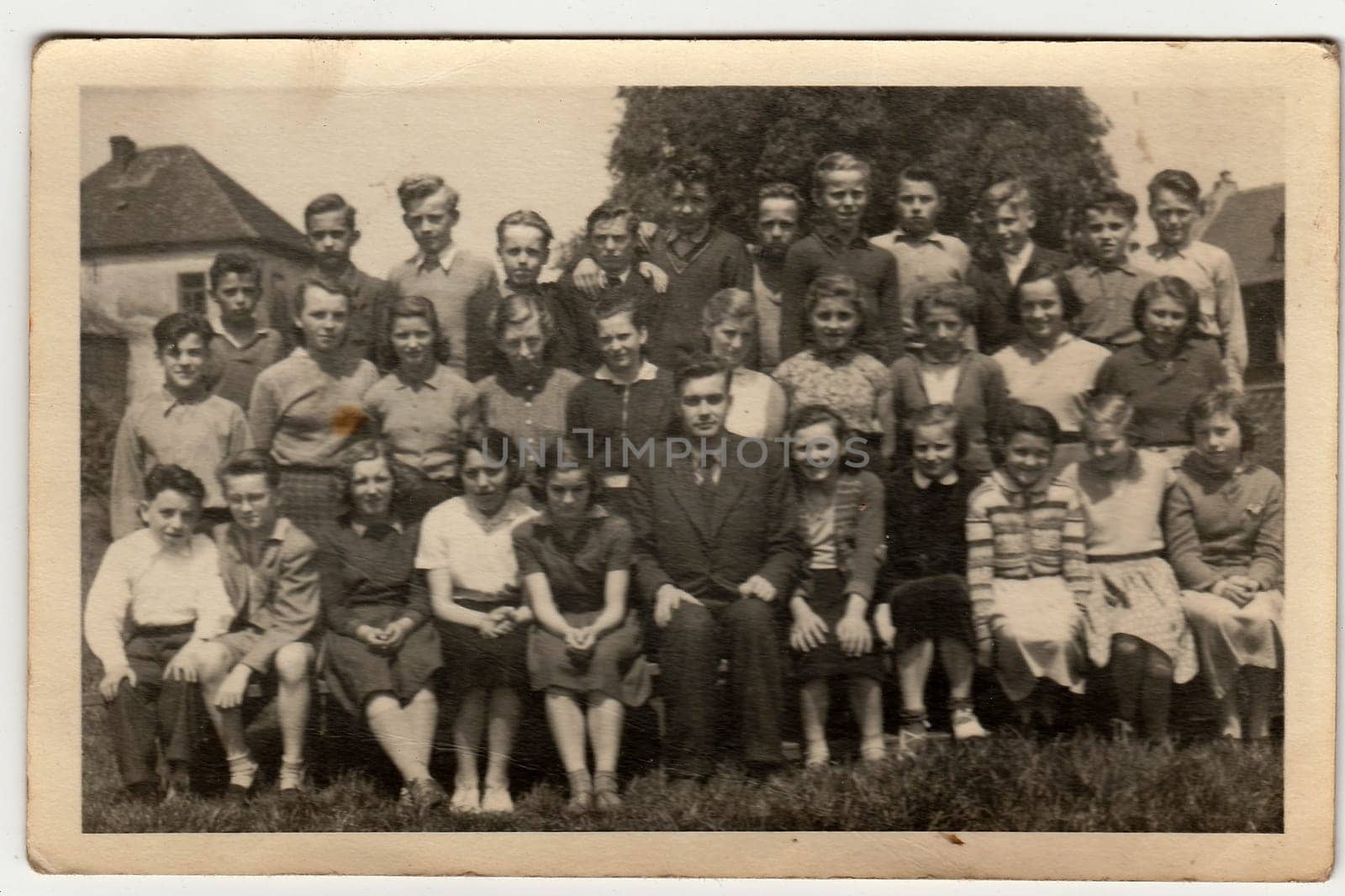 A vintage photo shows schoolmates with male teacher. by roman_nerud