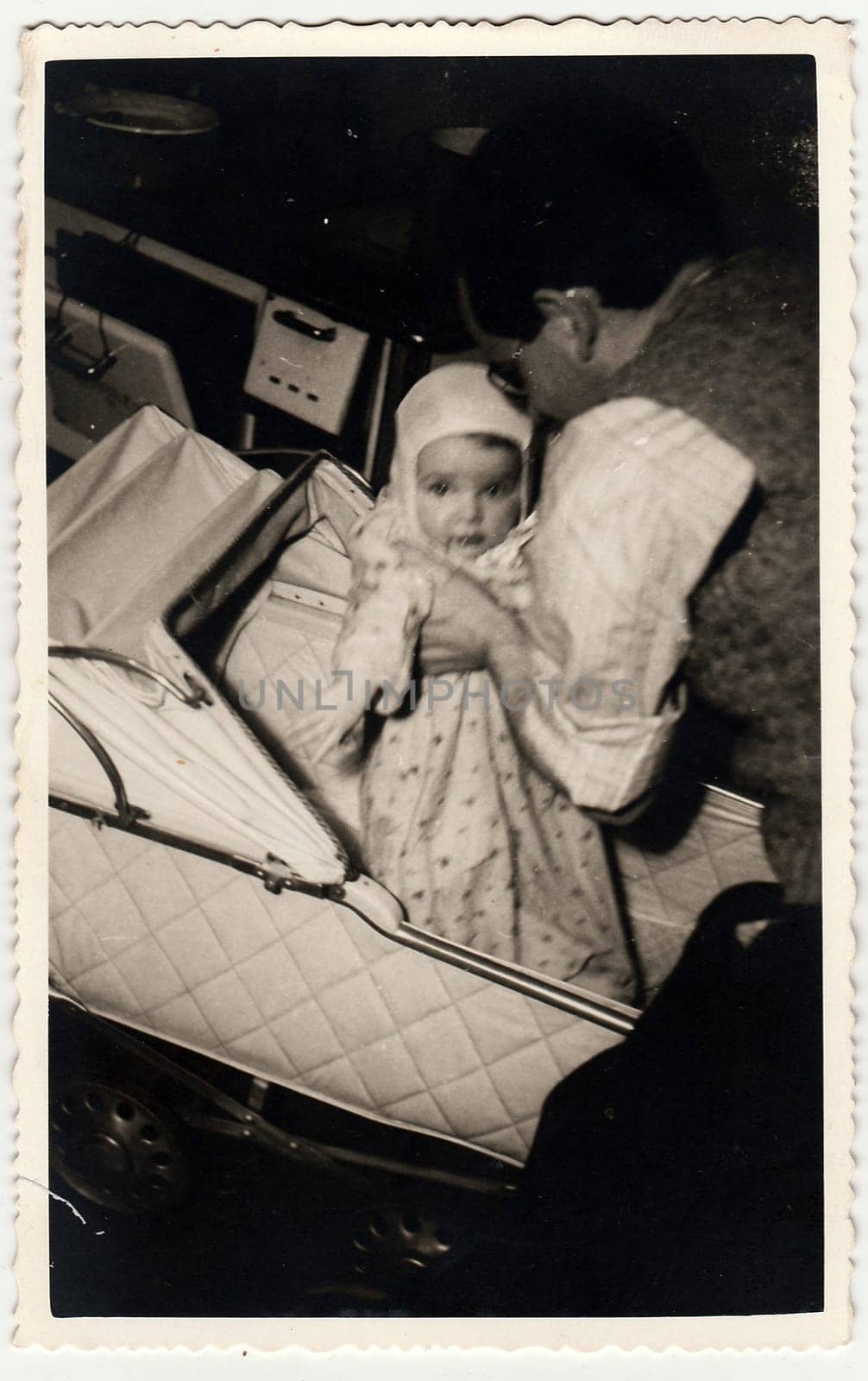 A vintage photo shows small baby girl, her father and pram (baby carriage). by roman_nerud