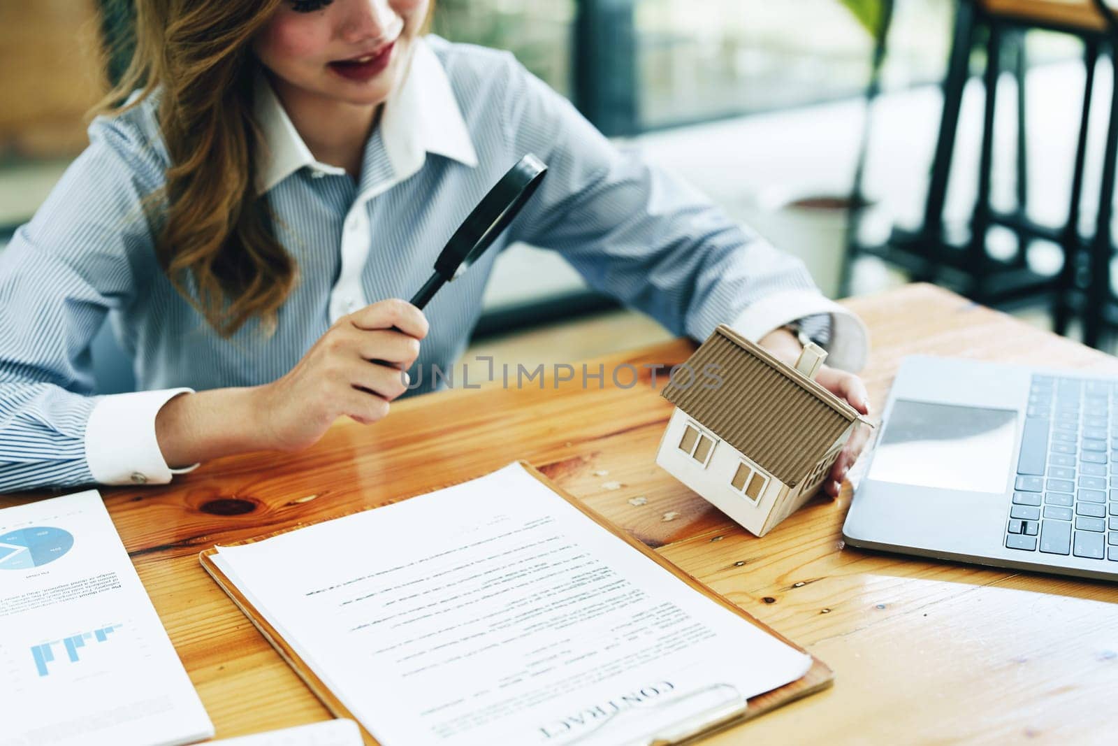 customer holding a magnifying glass to look at a house model, concept of home inspection before buying a house and land