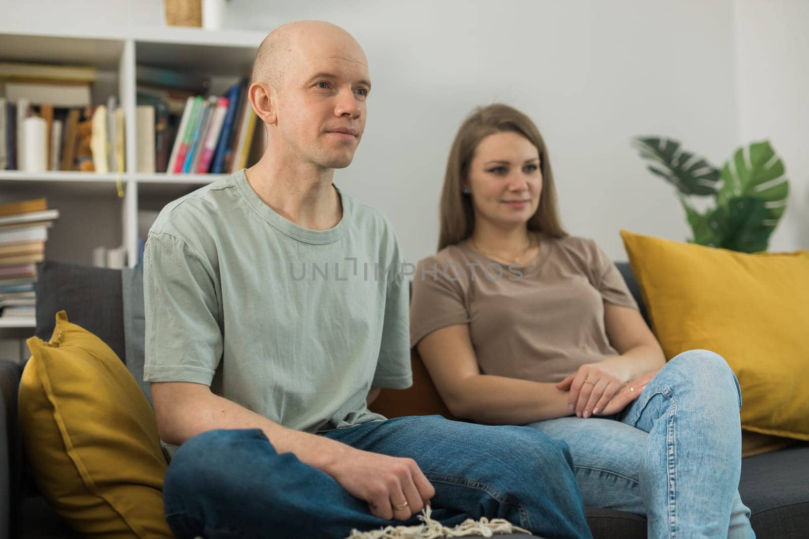 Young couple relaxing and watching TV at home, they focus on a dramatic moment in film - streaming service and free time concept by Satura86