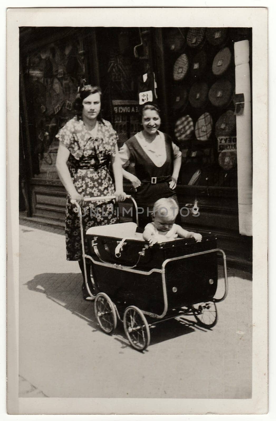 A vintage photo shows women go for a walk with pram baby carriage . Antique black white photo. by roman_nerud