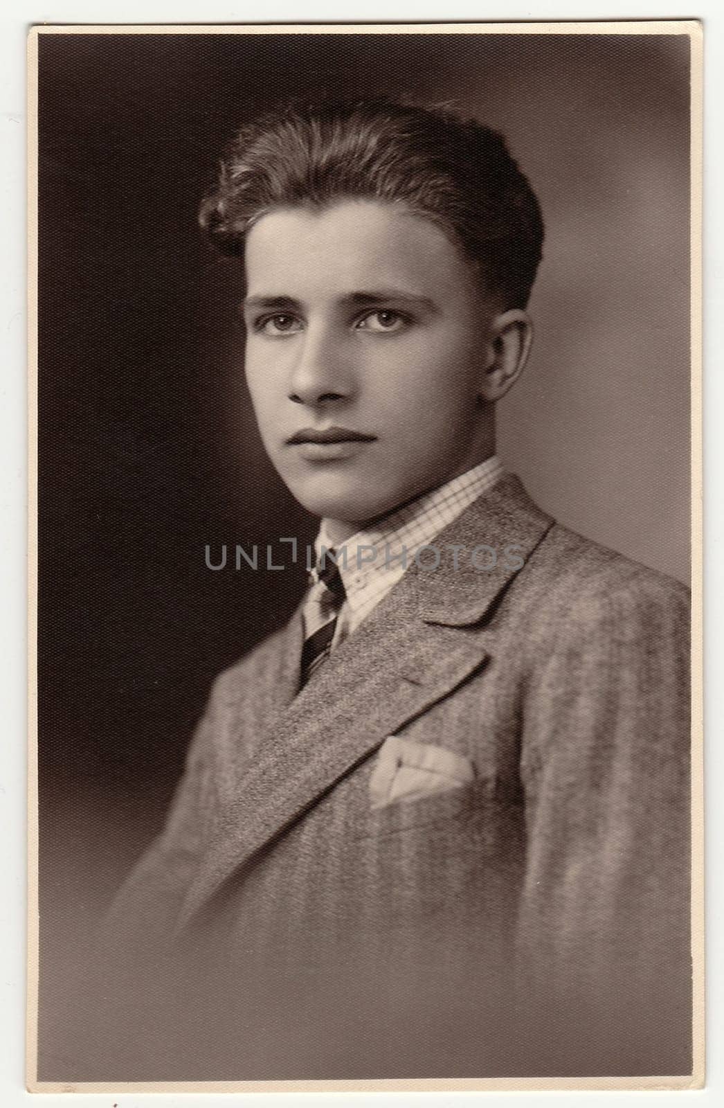 A vintage studio photo shows young man wears posh jacket. Antique black white photo. by roman_nerud