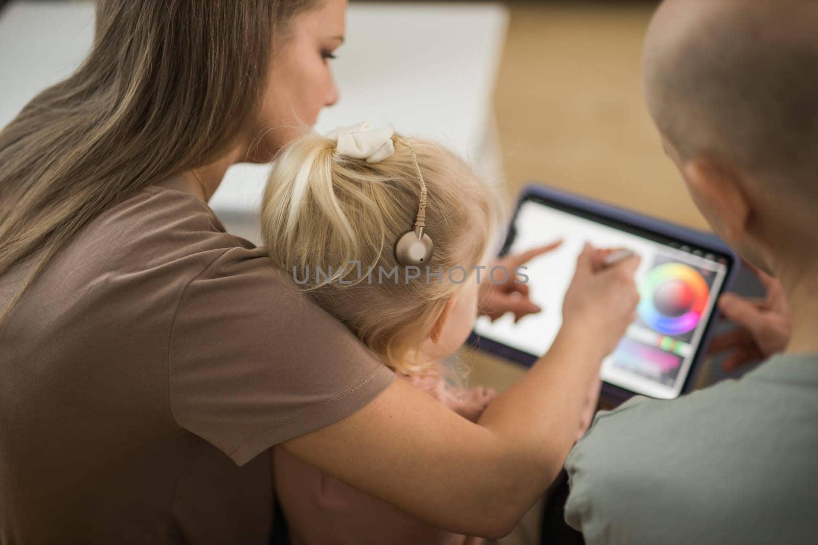 Deaf child girl with cochlear implant studying to hear sounds and have fun with mother and father - recovery after cochlear Implant surgery and rehabilitation concept by Satura86