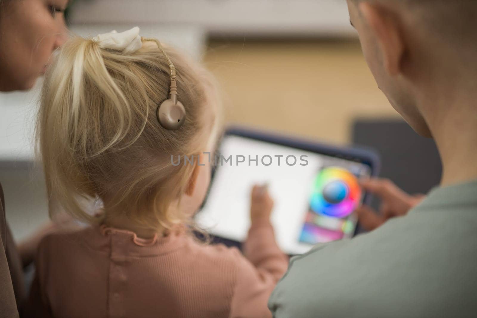 Deaf child girl with cochlear implant studying to hear sounds and have fun with mother and father - recovery after cochlear Implant surgery and rehabilitation concept by Satura86