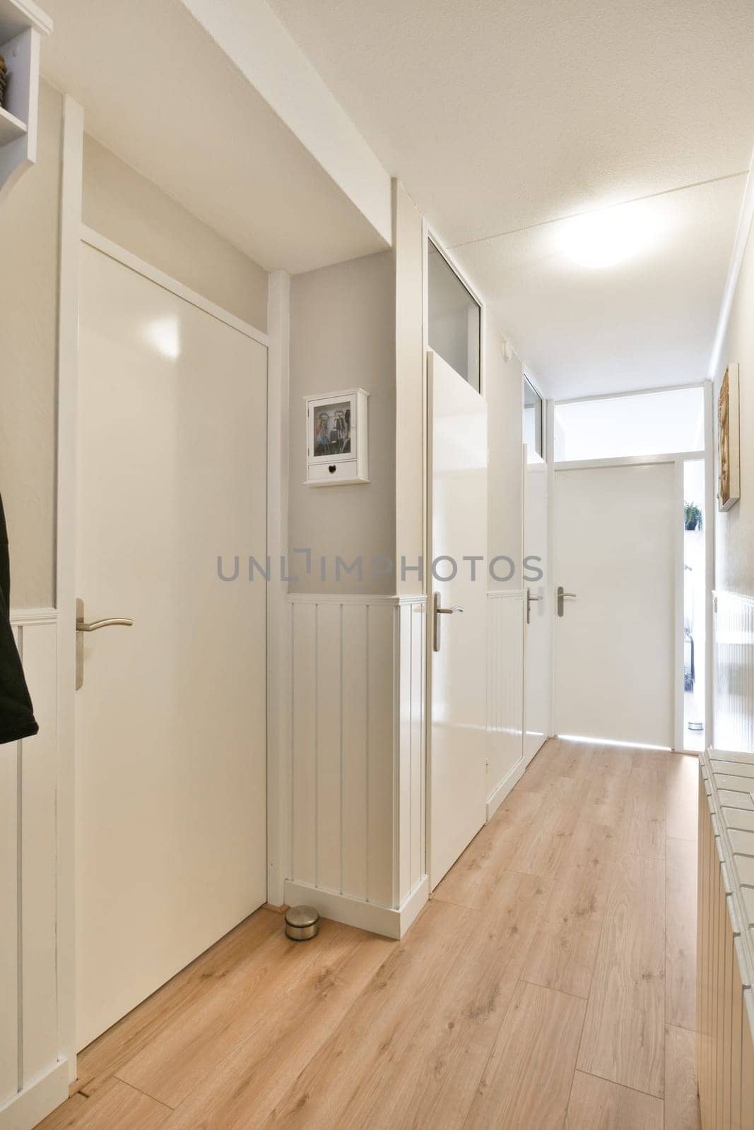 a hallway with white doors and a wood floor by casamedia