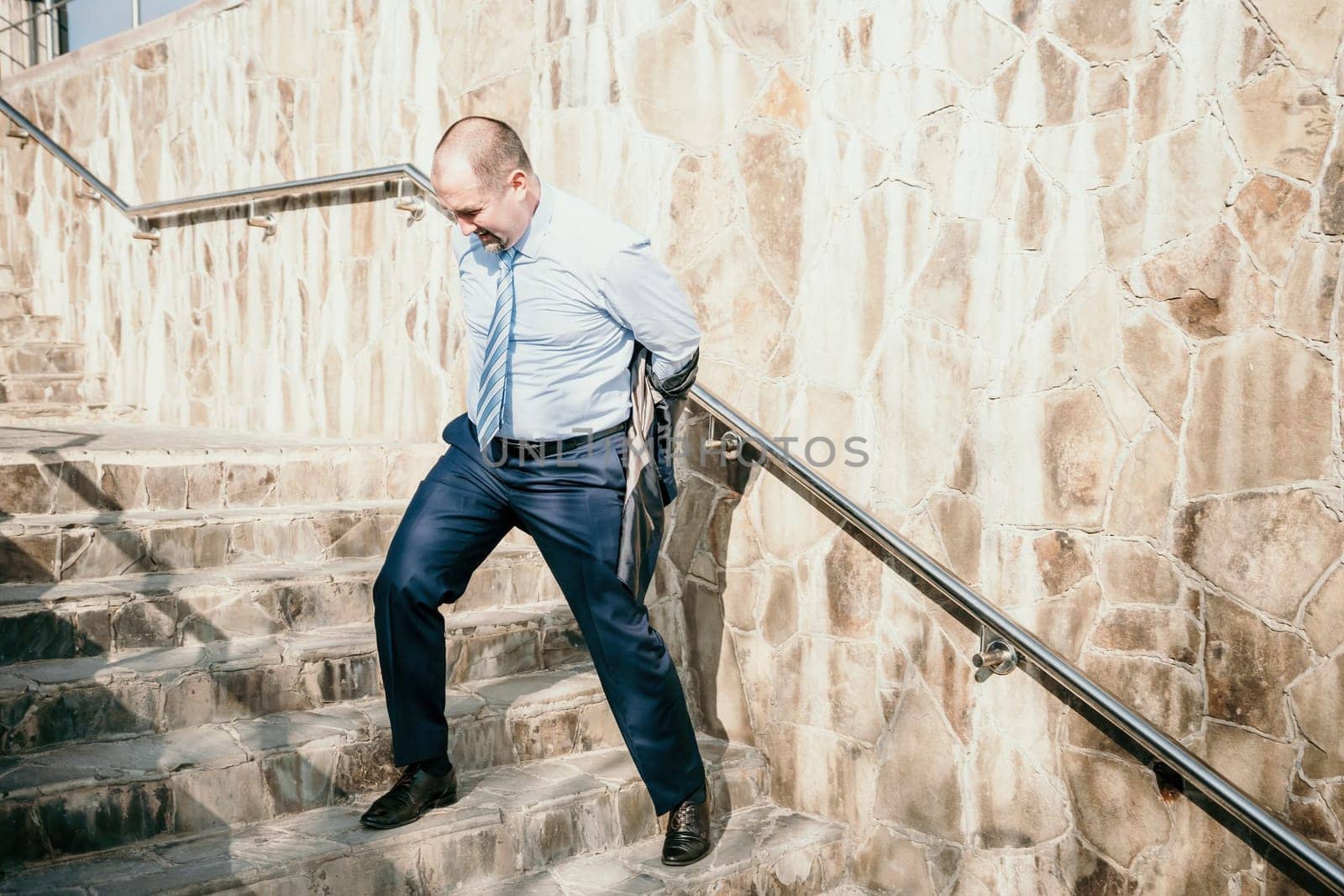 Portrait of a senior professional man in a suit with various problems. A middle-aged businessman with a briefcase descends the stairs.