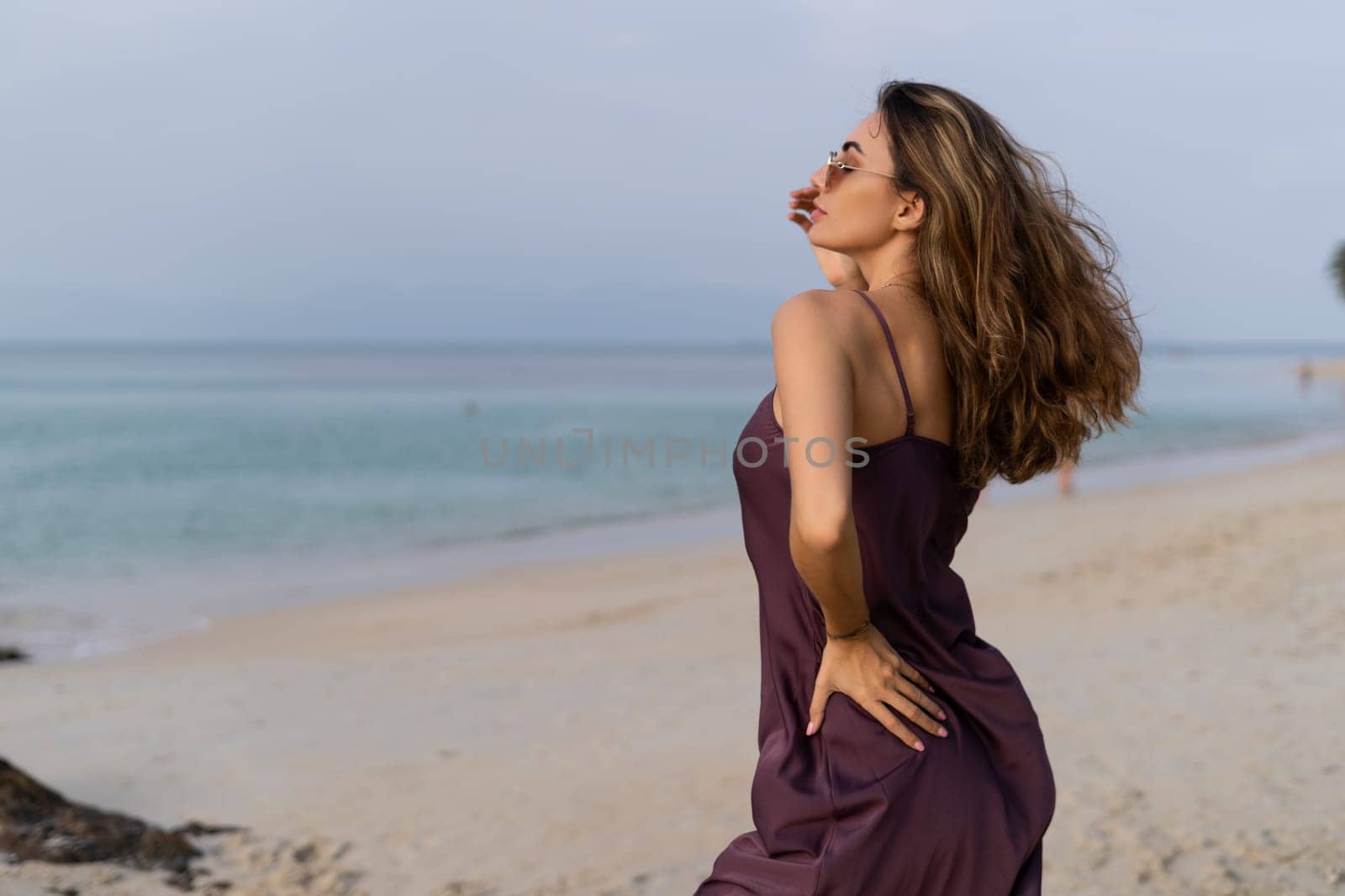 Stylish romantic tender sensual woman in silk dress and sunglasses on the beach at sunset by kroshka_nastya