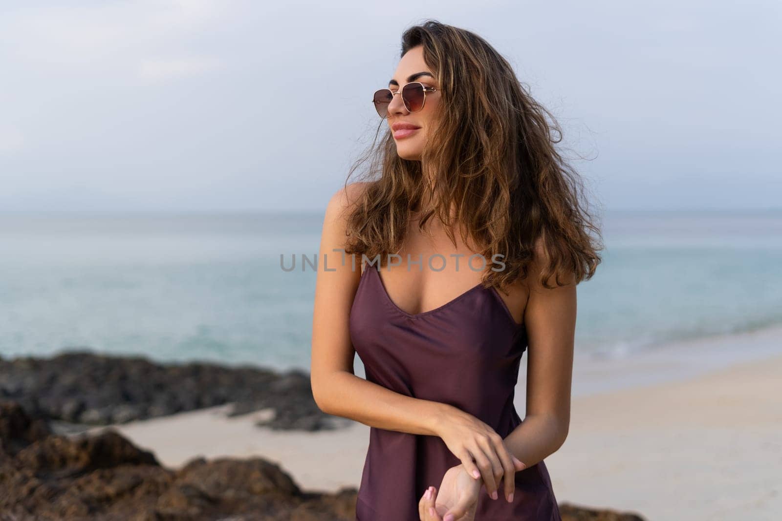 Stylish romantic tender sensual woman in silk dress and sunglasses on the beach at sunset by kroshka_nastya