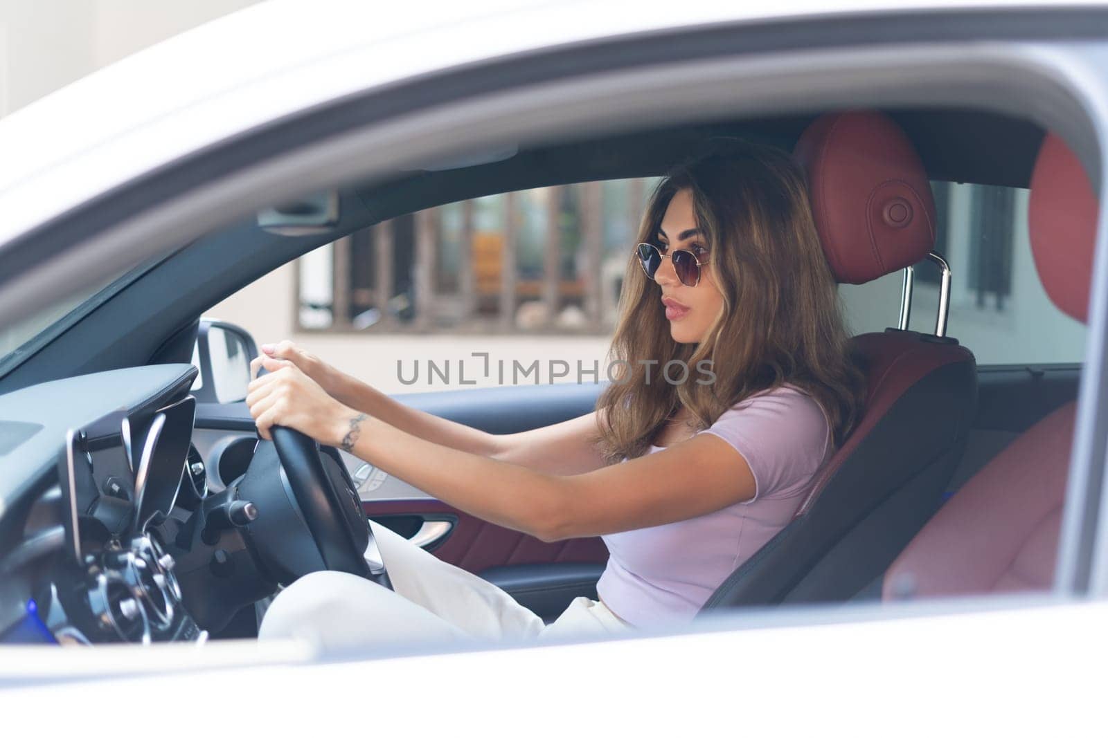 Beautiful young happy smiling woman driving her expensive luxury car, serious focused face