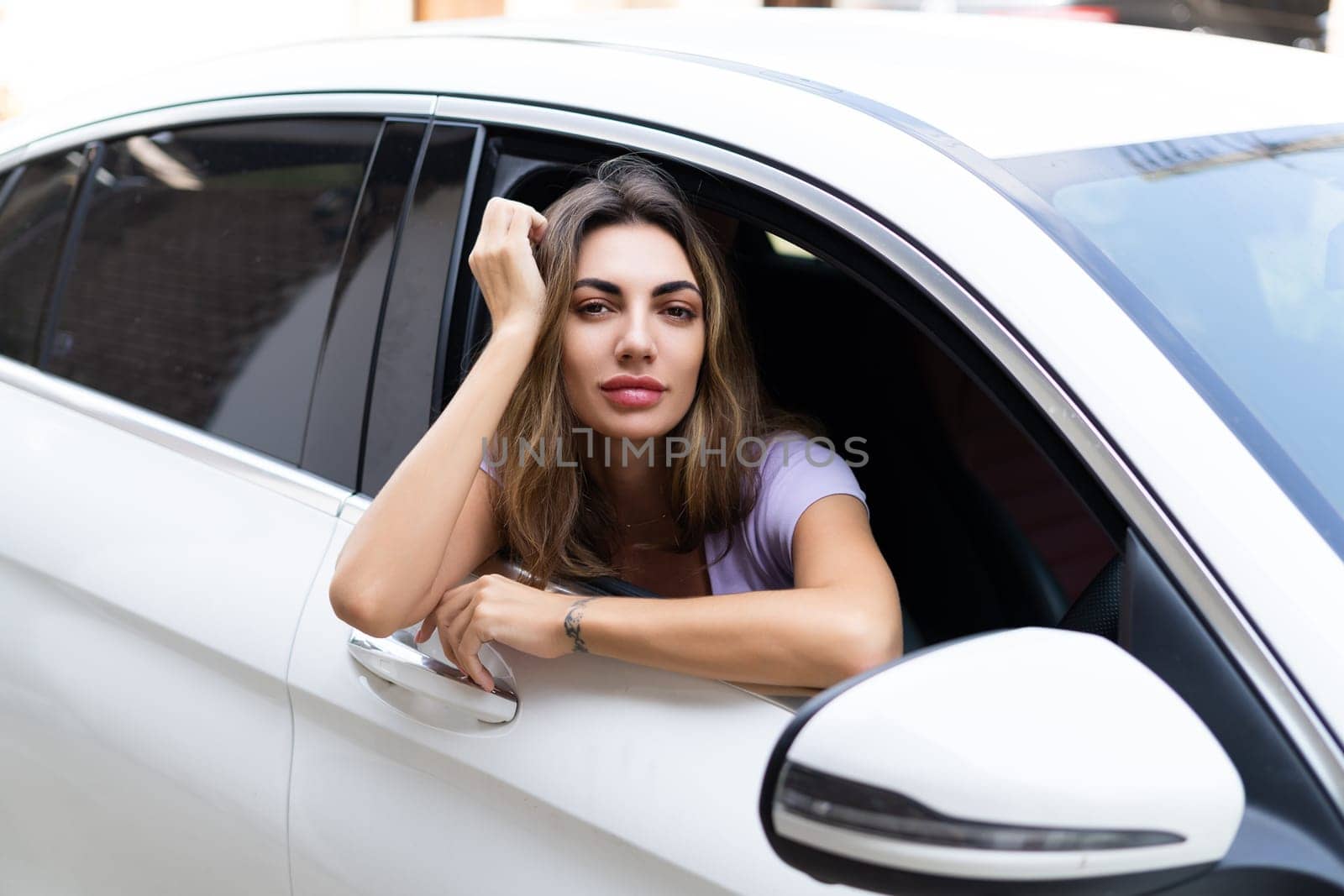 Beautiful young happy smiling woman driving her car, sitting behind the wheel, looking out the window