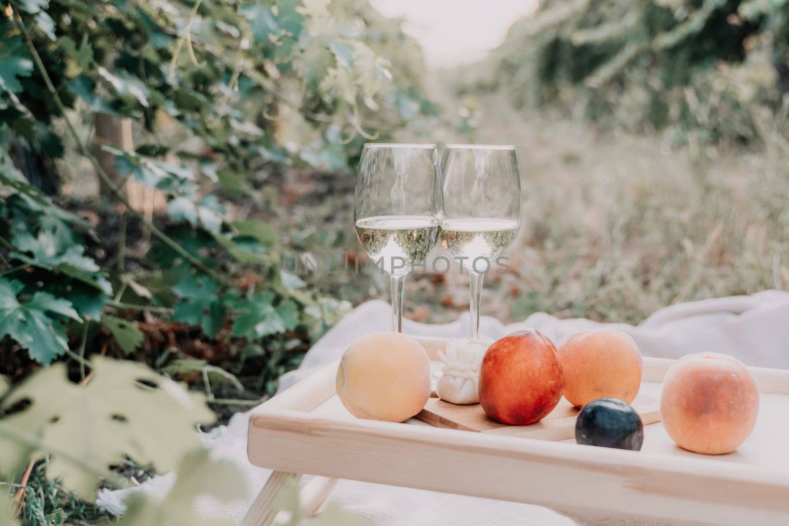 Woman picnic vineyard. Happy woman with a glass of wine at a picnic in the vineyard, wine tasting at sunset and open nature in the summer. Romantic dinner, fruit and wine. by panophotograph