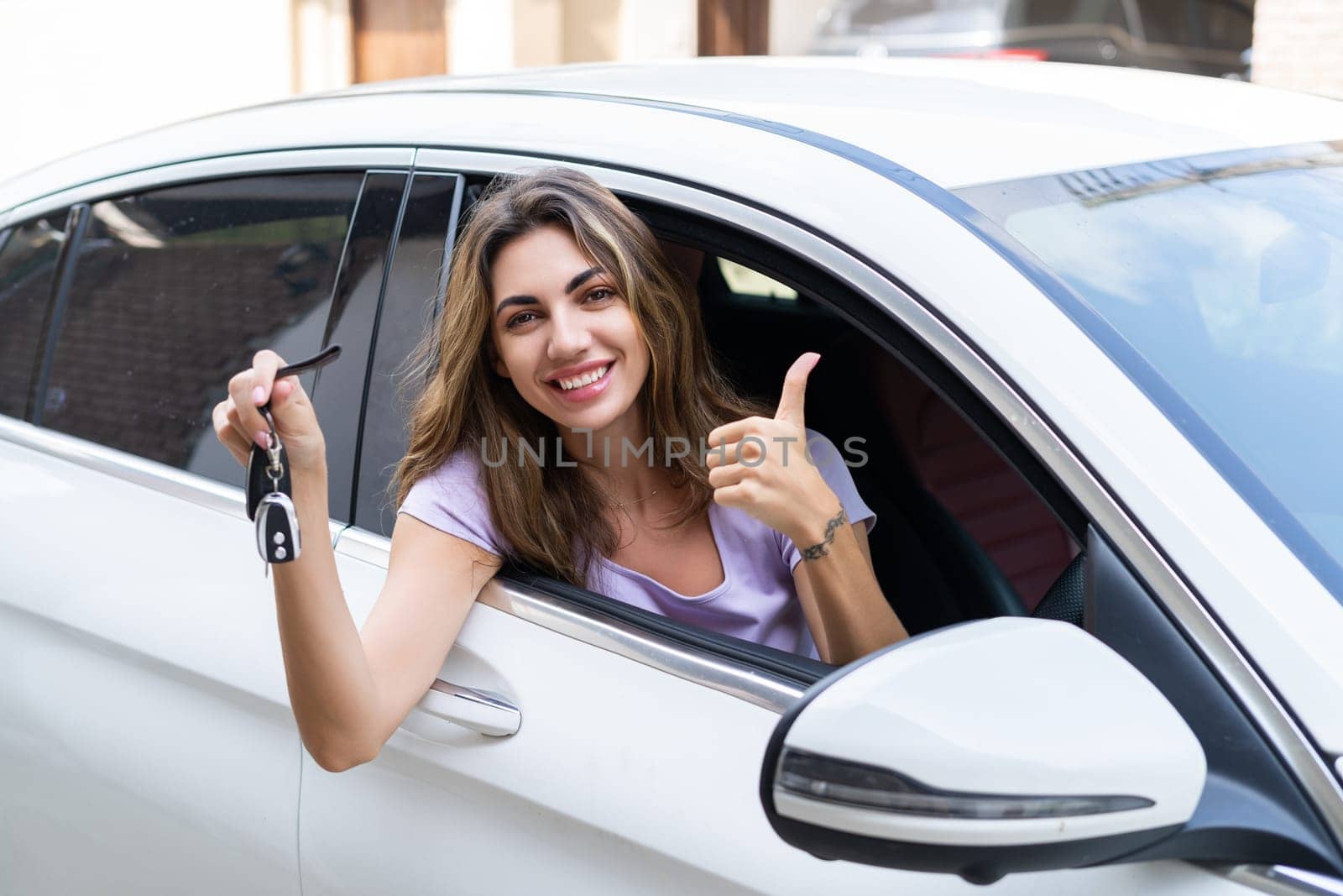 Beautiful young happy smiling woman driving her car, showing the keys to a new car