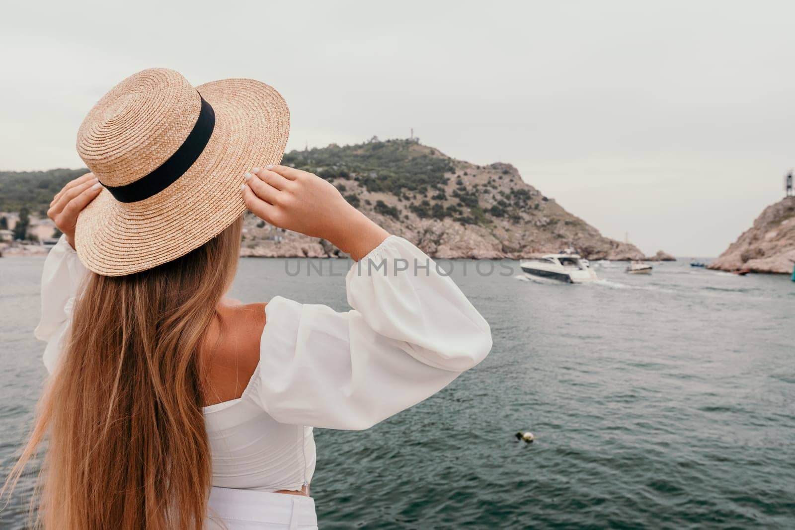Woman summer travel sea. Happy tourist in hat enjoy taking picture outdoors for memories. Woman traveler posing on the beach at sea sharing travel adventure journey by panophotograph