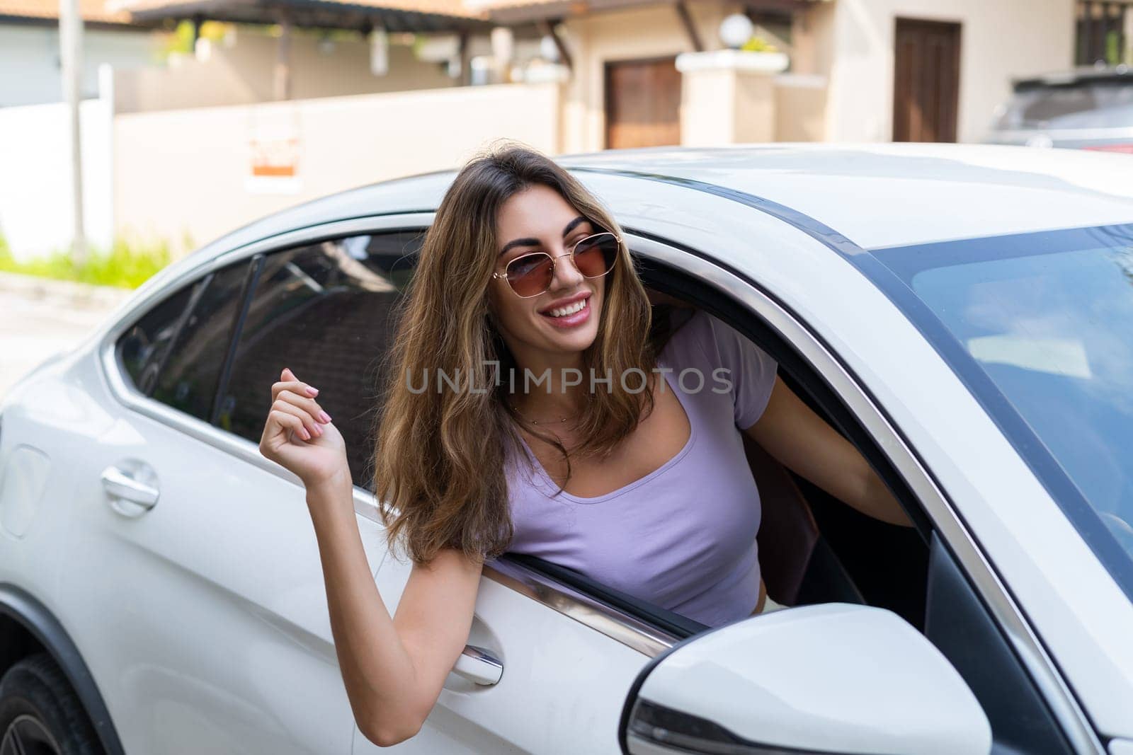Beautiful young happy smiling woman driving her car, sitting behind the wheel, looking out the window by kroshka_nastya