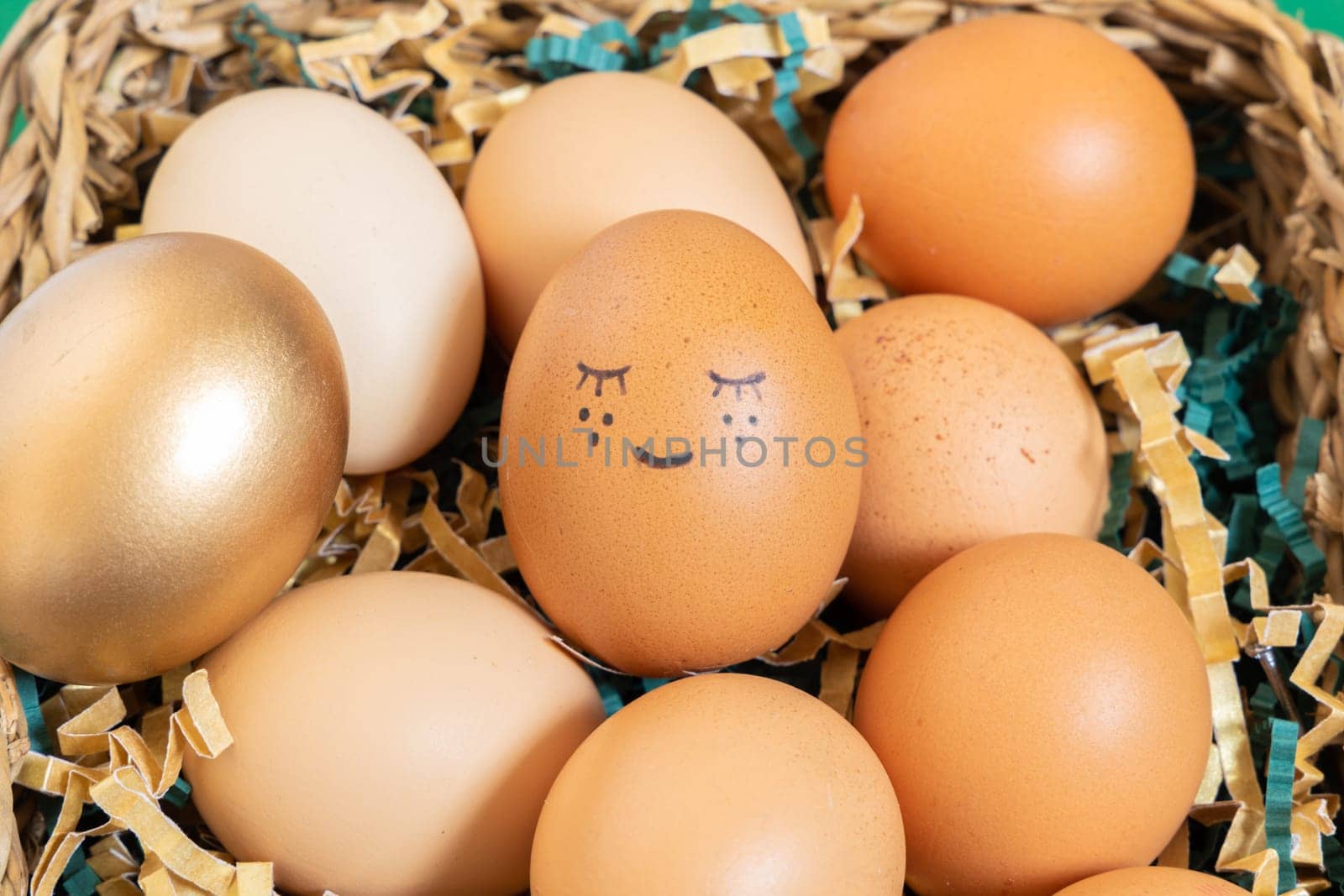 Close up of easter eggs with funny face natural and gold in basket with paper filler.