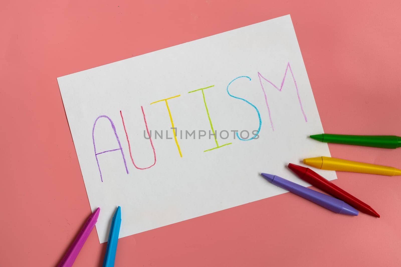Text word autism on paper sheet written by colorful letter, on blue background