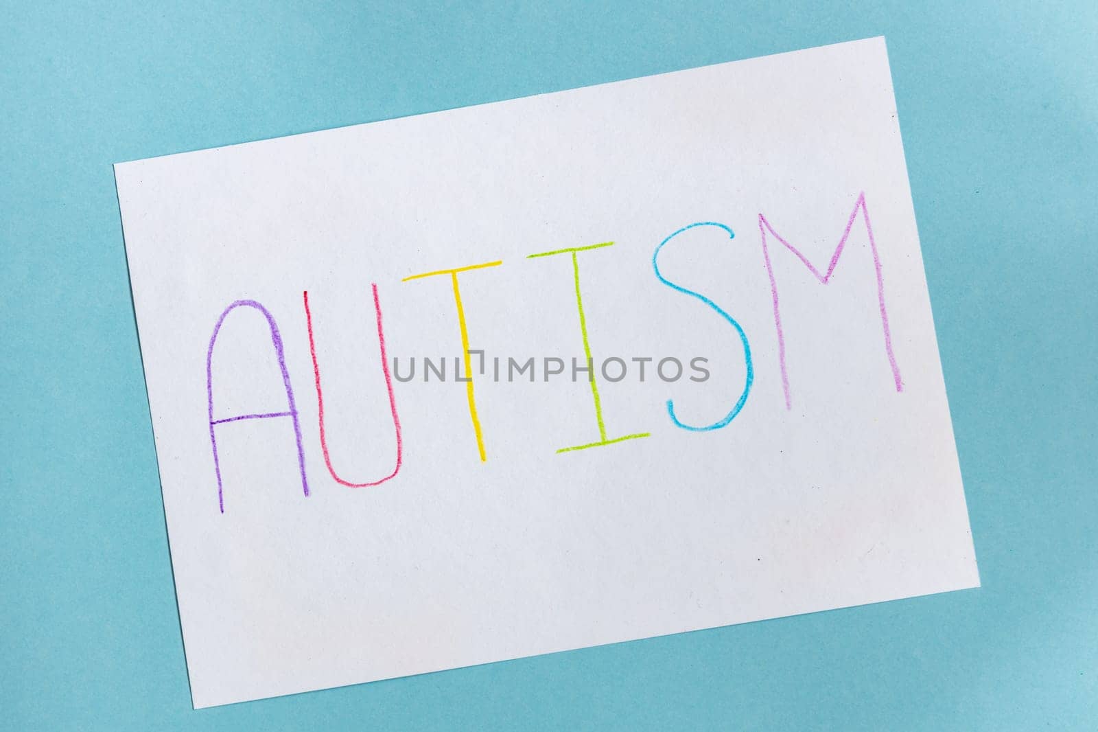 Text word autism on paper sheet written by colorful letter, on blue background. by Ri6ka