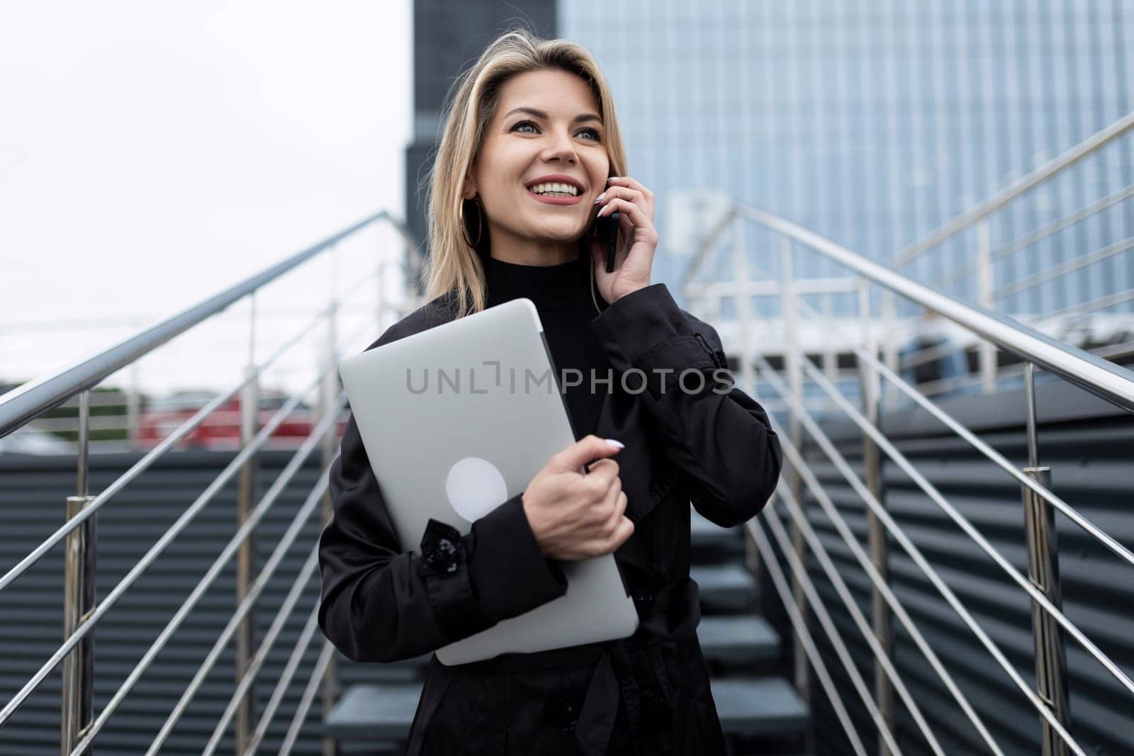 confident female european leader speaks on the phone on the background of the business center.