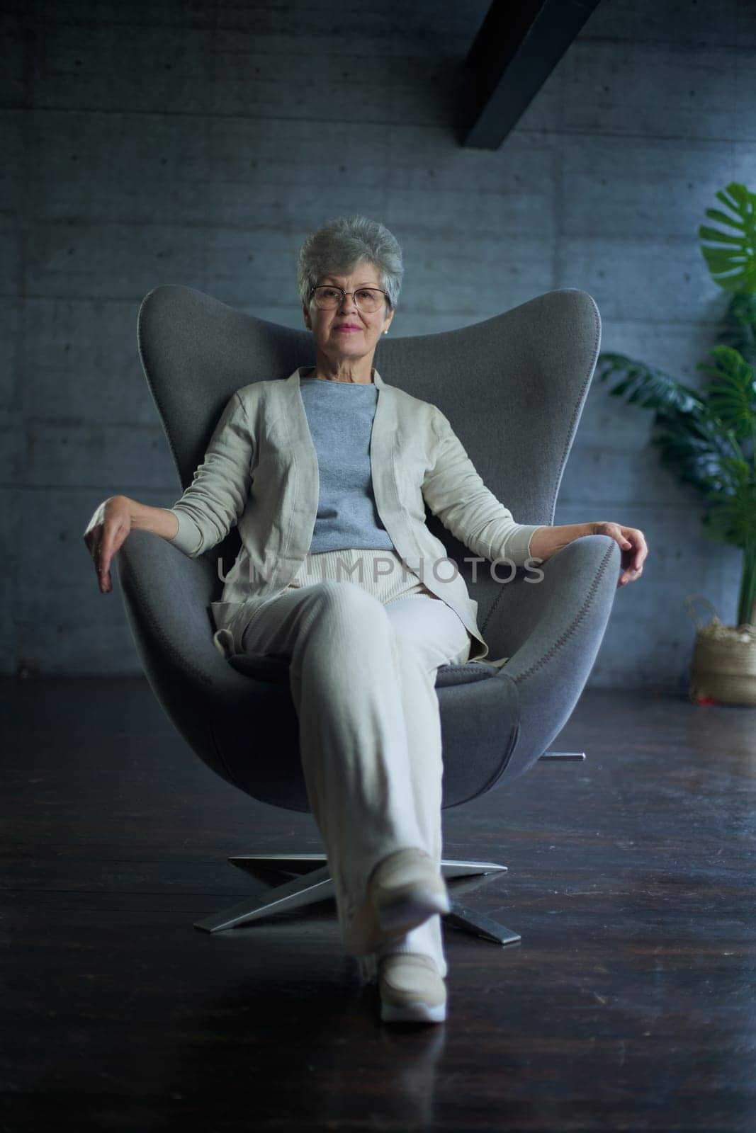 attractive middle aged smiling woman model sitting in chair looking at camera at office