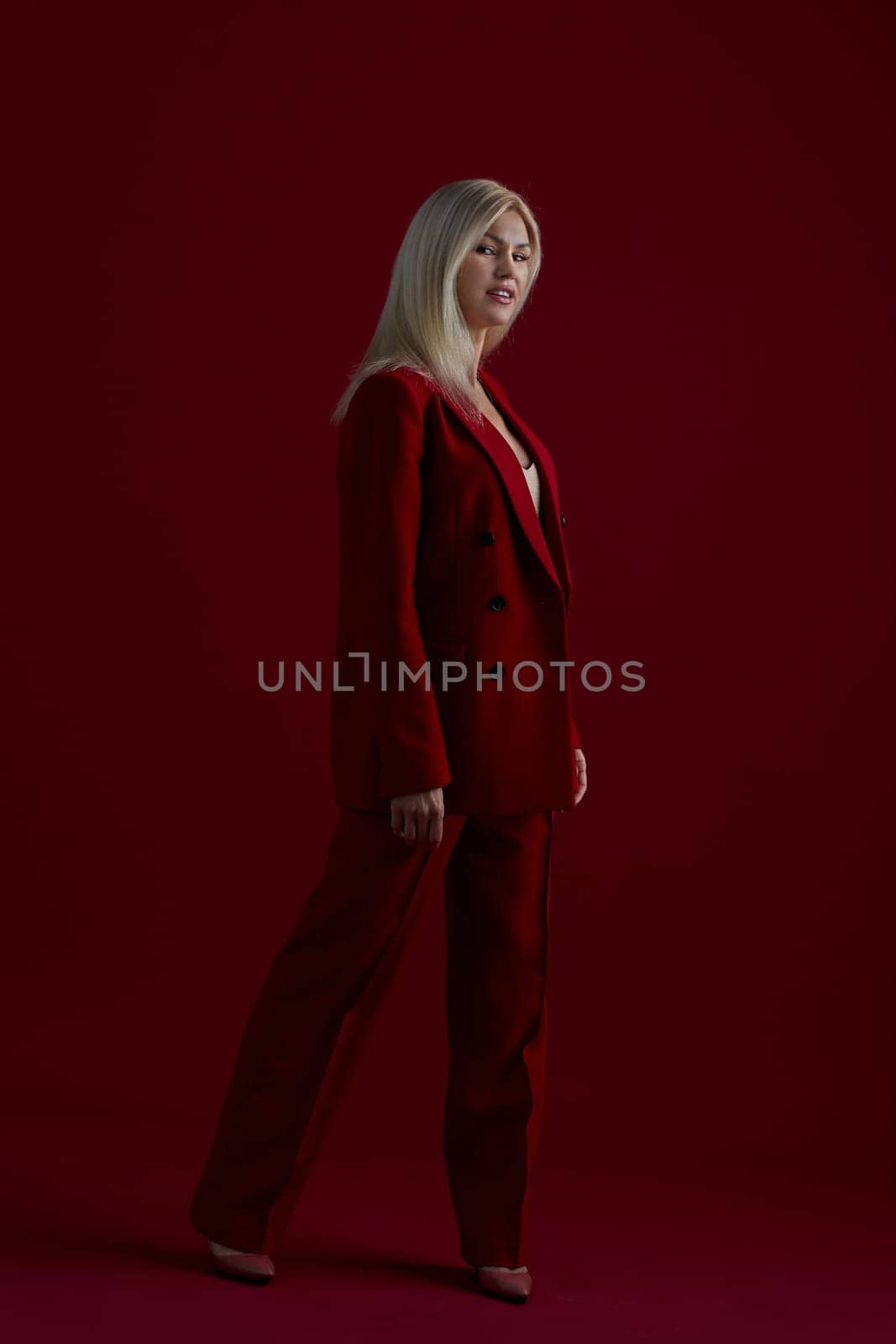 Portrait of a blonde woman in red dress on a red background