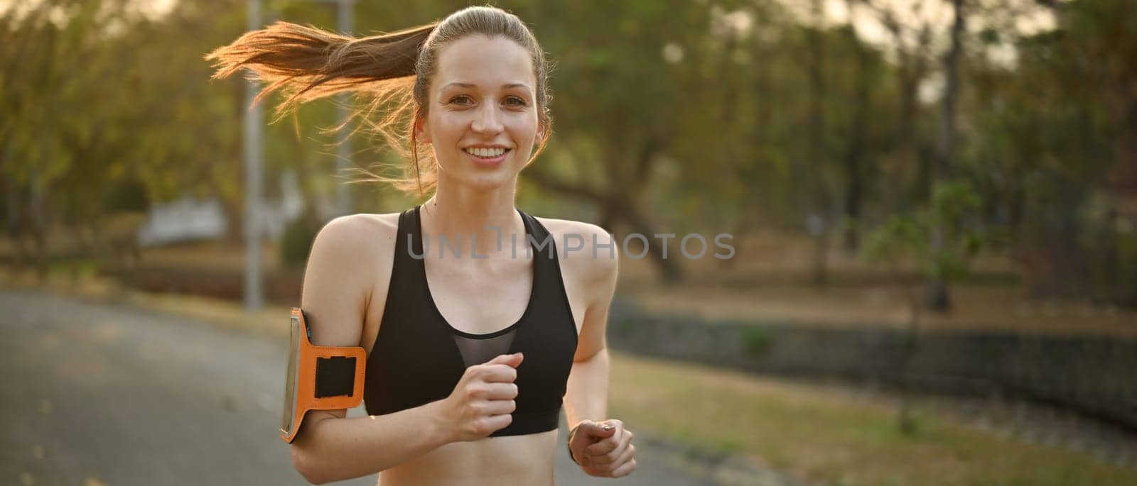 Athletic caucasian woman in sportswear jogging in public park. Fitness, sport and healthy lifestyle concept.