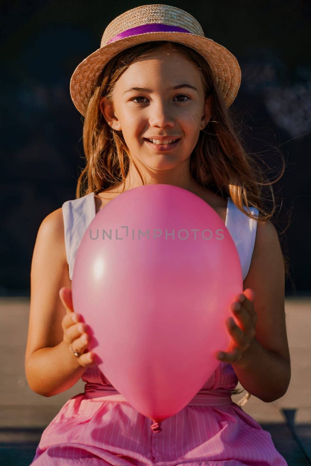 Portrait of a girl in a hat with a pink balloon. She is dressed in pink clothes and her hair is long and loose. by Matiunina