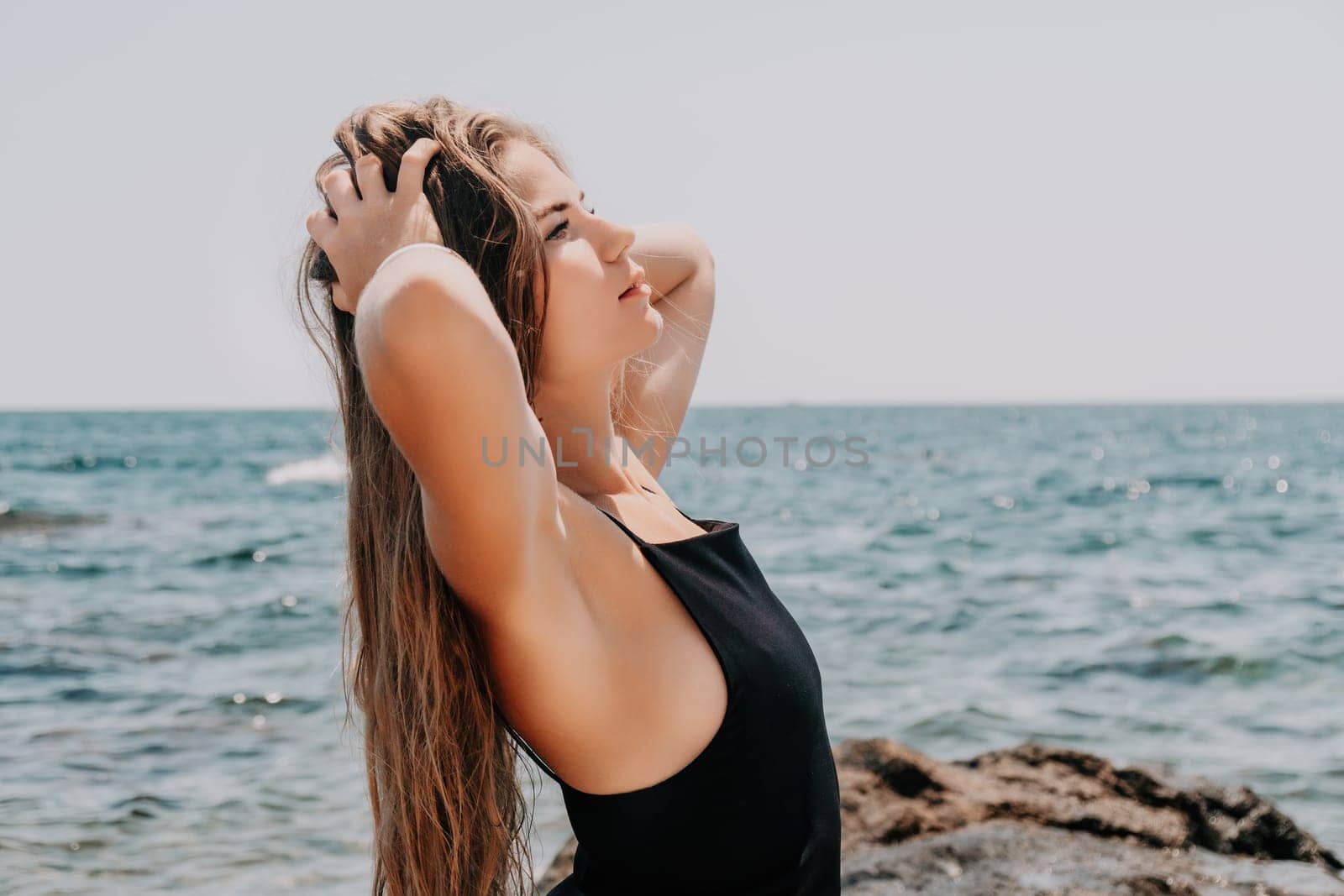 Woman travel sea. Young Happy woman in a long red dress posing on a beach near the sea on background of volcanic rocks, like in Iceland, sharing travel adventure journey