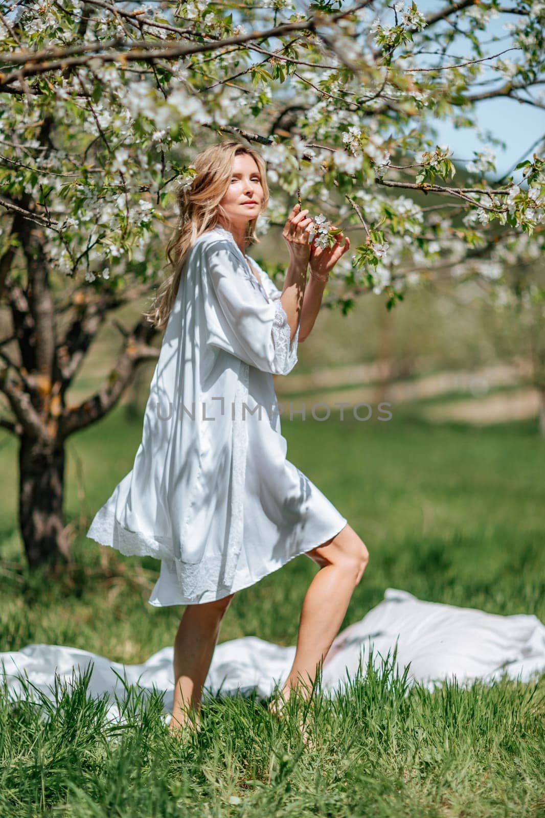 Portrait of a blonde in the park. Beautiful woman with long blond hair in a blue dress