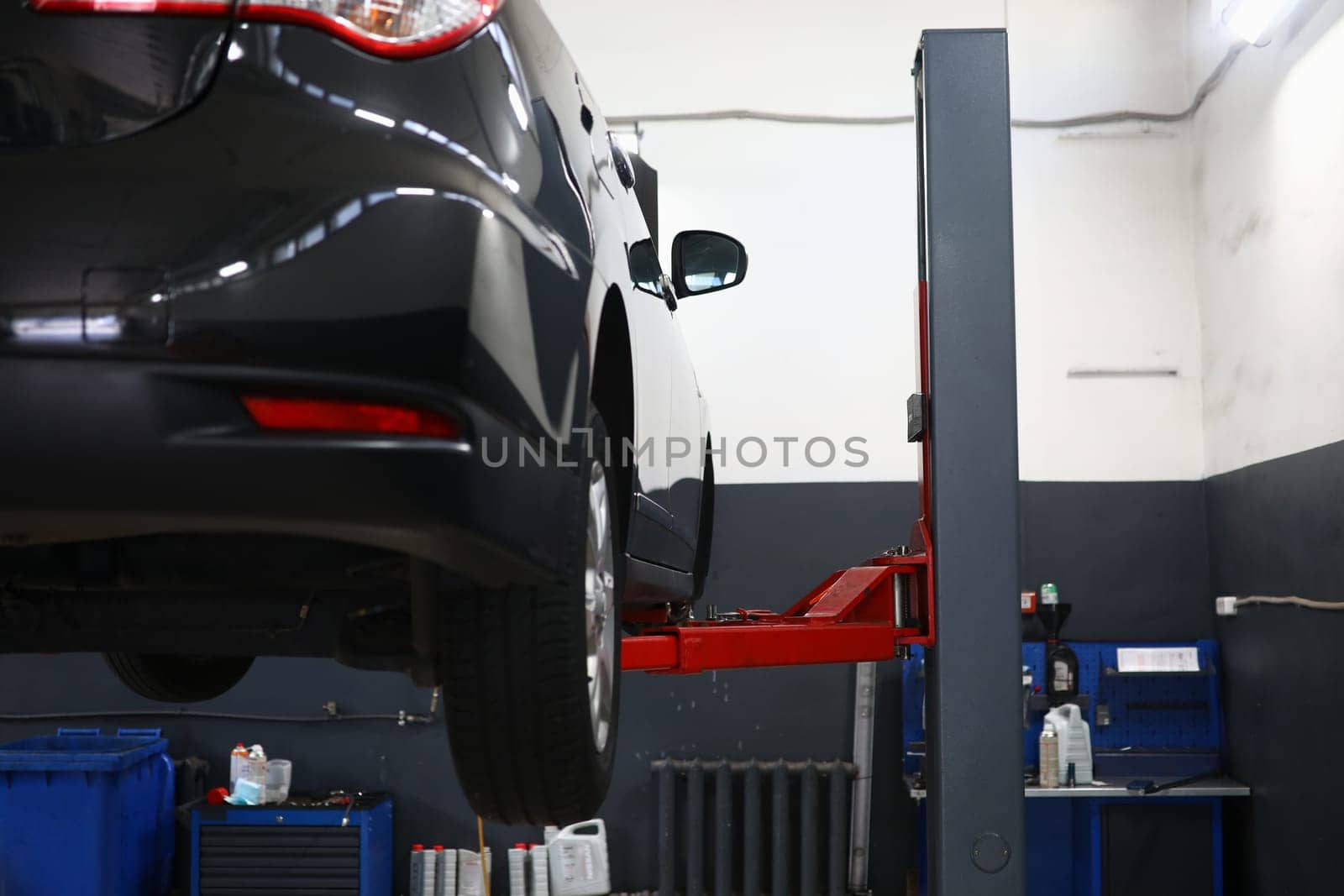 Modern car on lift in service center. Car insurance and repair service concept