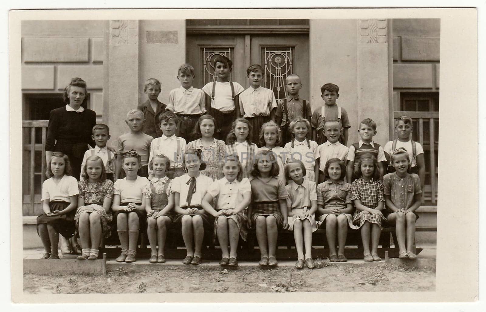 Vintage photo shows pupils (schoolmates) and their female teacher. by roman_nerud