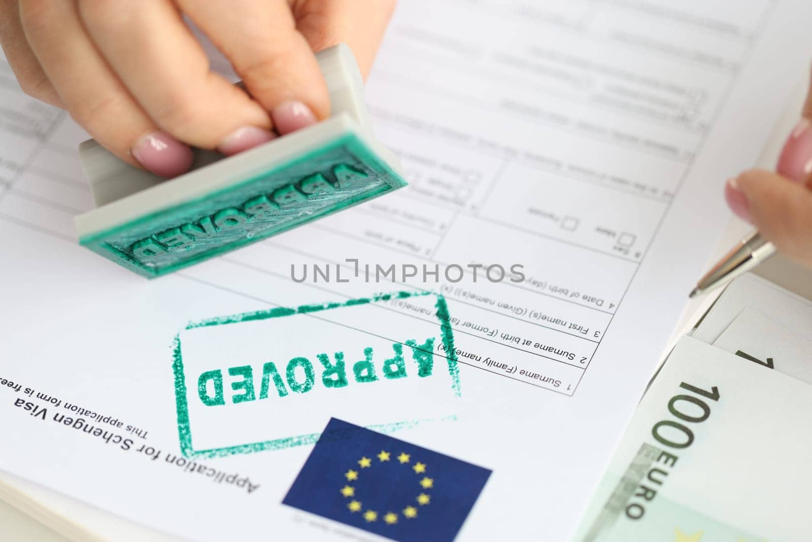 Approval of visa for travel to European Union, an employee of embassy puts stamp. Getting Schengen visa concept