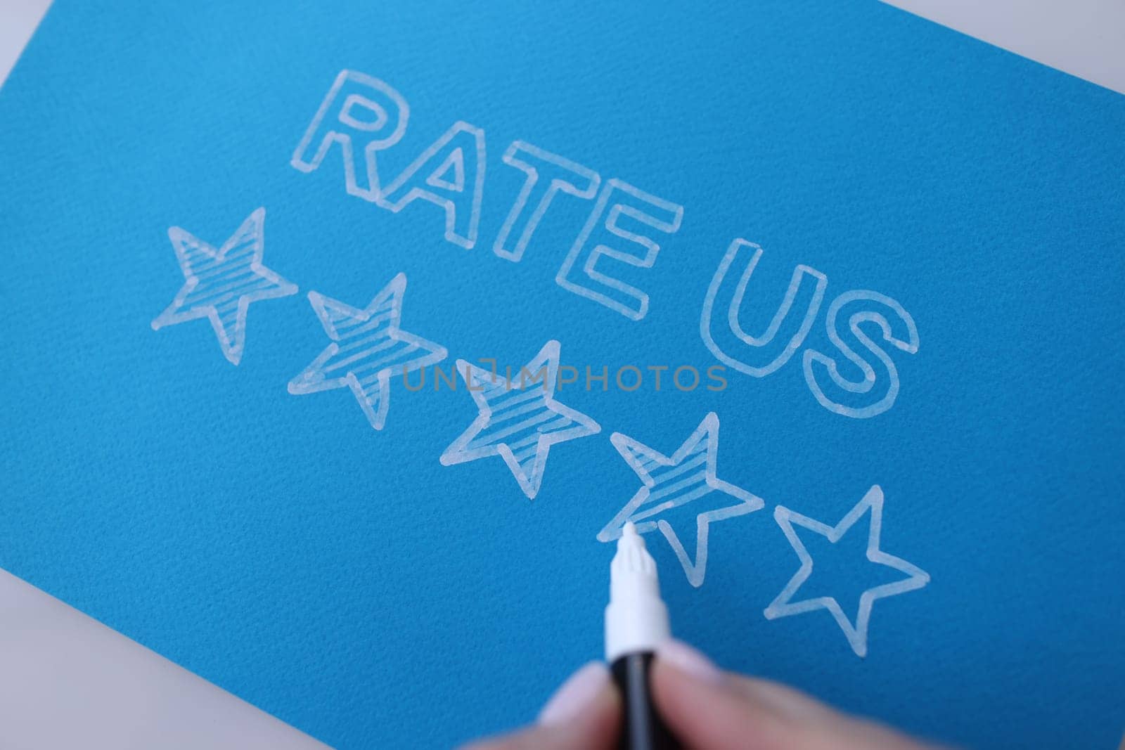 Handwritten review rate us and star rating on blue background. Customer feedback and service recommendation concept