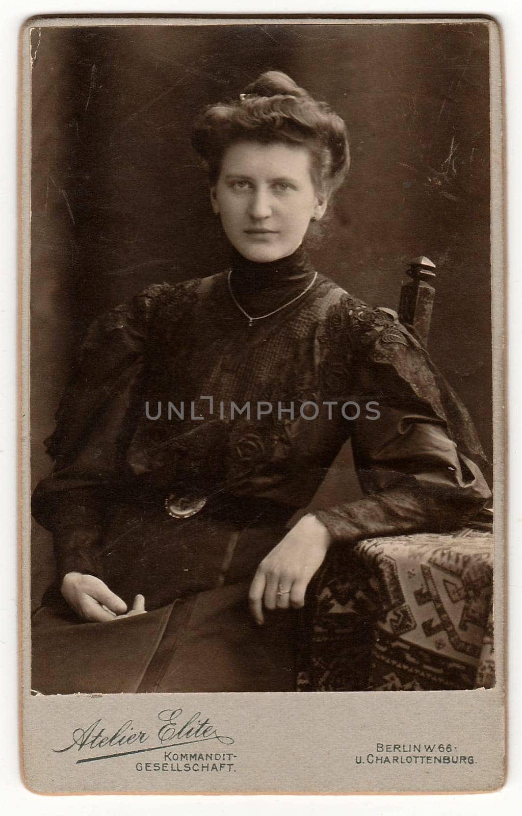 BERLIN, GERMANY - CIRCA 1895: Vintage cabinet card shows woman with Victorian and Edwardian hair style sits at the table. Antique black white photo.